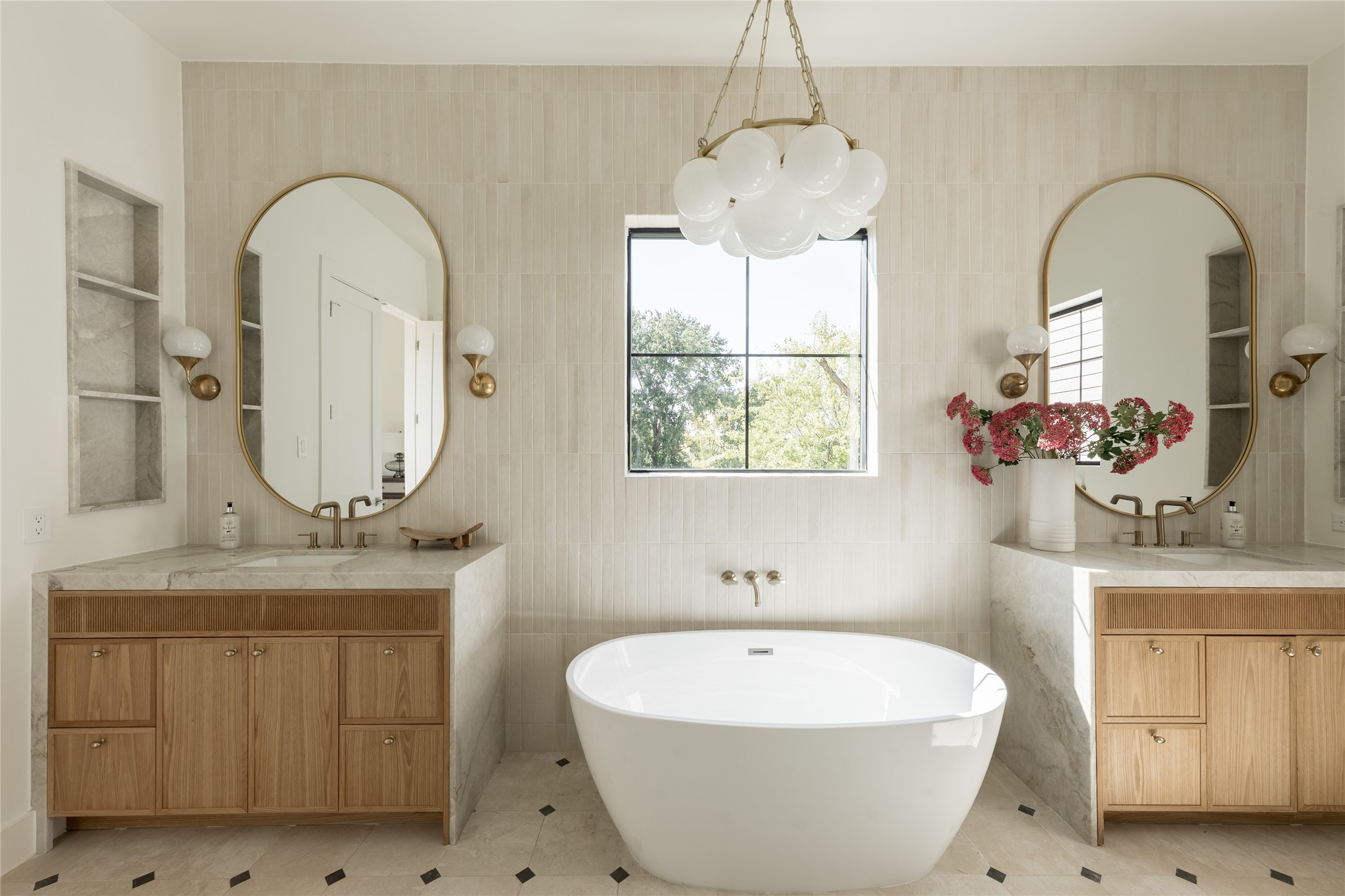 The spa inspired primary bath centers on a freestanding soaking tub, framed by natural stone, designer tile and sculptural lighting for a quietly dramatic focal point.