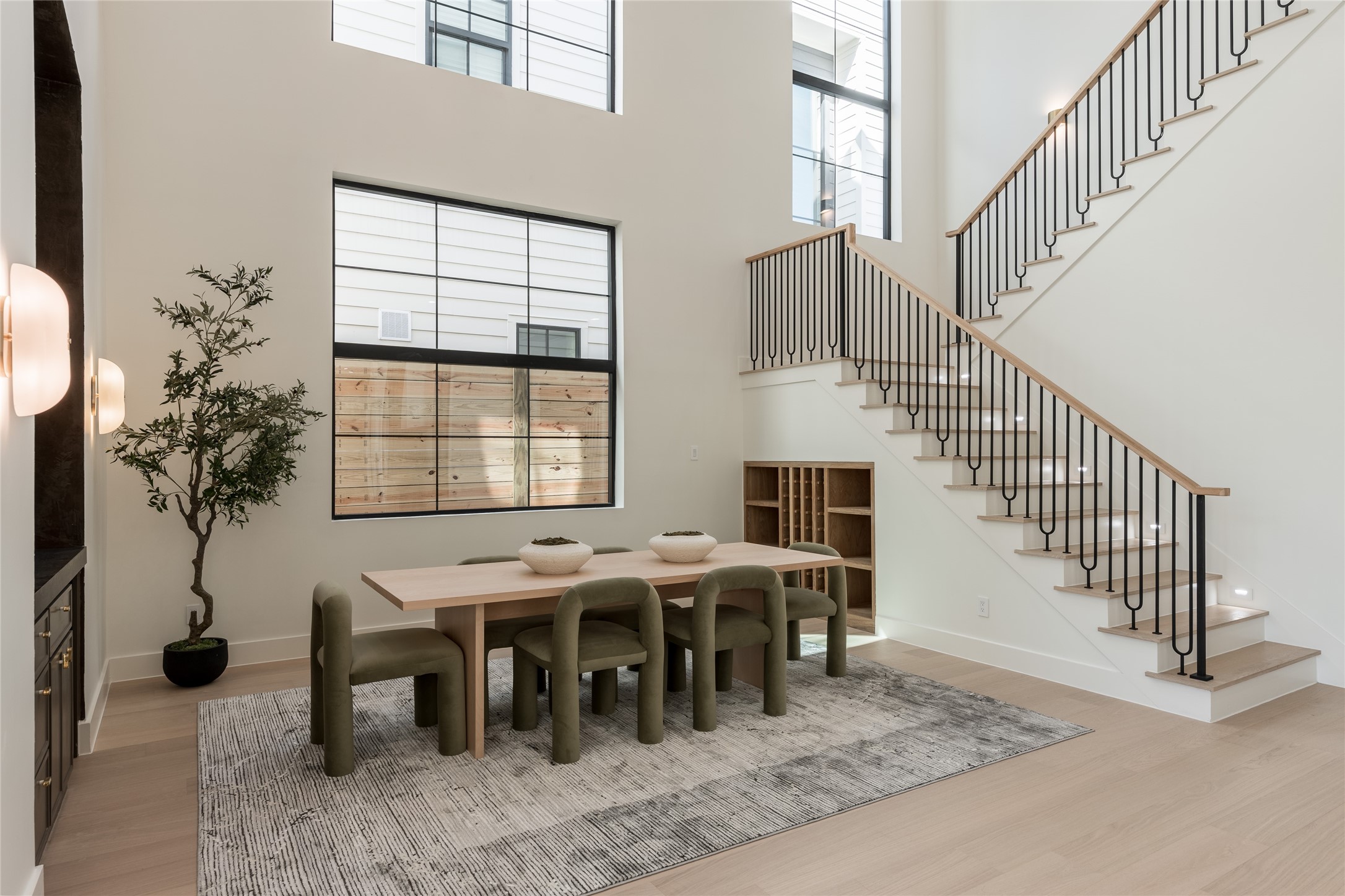 The dramatic two story dining room is framed by soaring windows that draw natural light through the space, while a dedicated dry bar and built in wine/display cove turn entertaining into part of the architecture.