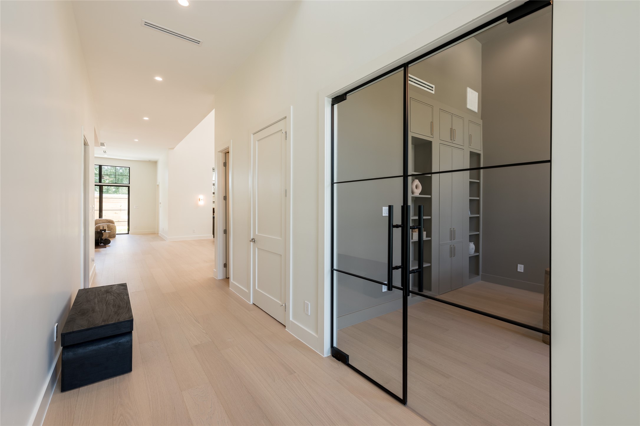 The foyer offers a striking introduction to the home, with clean sightlines leading toward the private study, where a glass entry adds architectural interest while preserving the openness of the space.