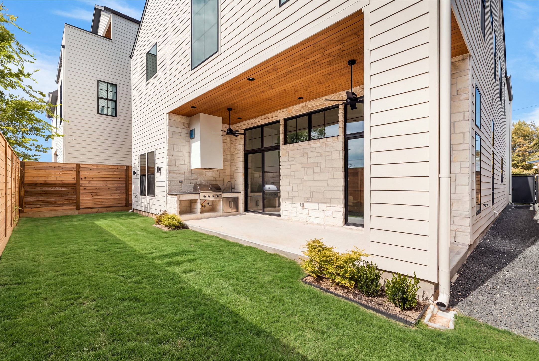 Extending beyond the covered patio, the backyard offers a welcome sense of openness with a long, uninterrupted lawn framed by privacy fencing. The outdoor kitchen and sheltered seating area establish a natural gathering place, while the surrounding green space provides flexibility for a variety of outdoor activities.