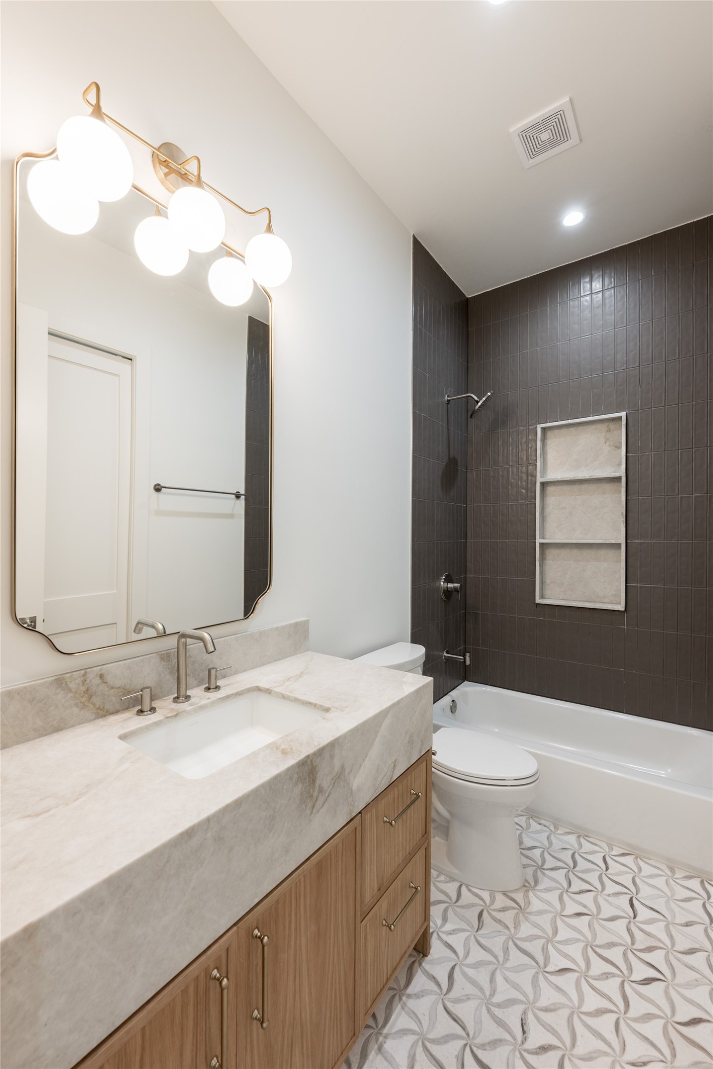 The mother-in-law suites private bath is finished with natural stone, full height designer tile and a glass enclosed shower, giving the first floor retreat the same level of finish found throughout the home.