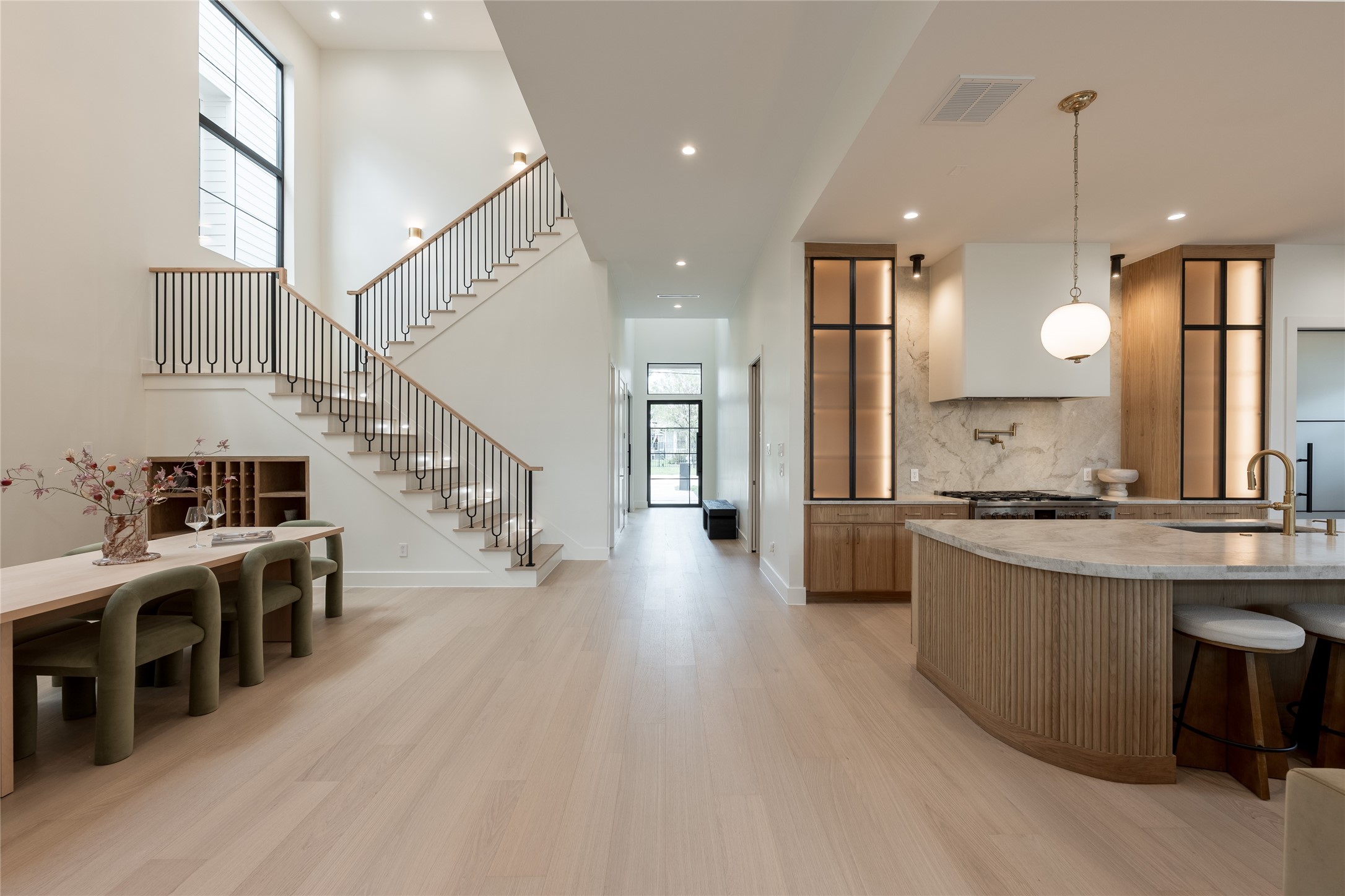 A long interior sightline reveals the homes scale and flow, with the two story dining room, custom white oak staircase and chefs kitchen unfolding seamlessly toward the great room beyond.