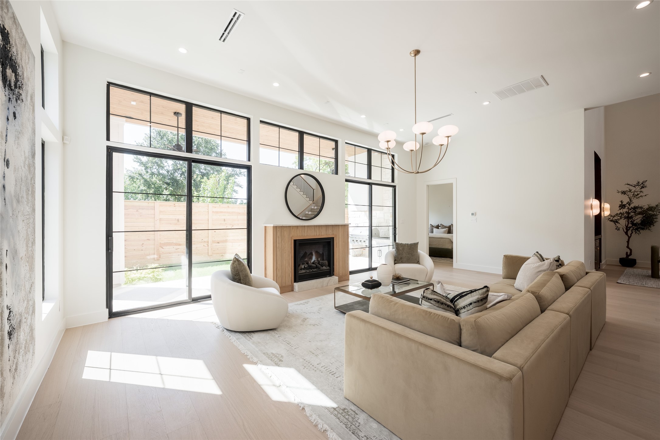 The great room balances dramatic scale with warmth, pairing 12 foot ceilings and a fluted fireplace with walls of grid windows that bring natural light deep into the space.