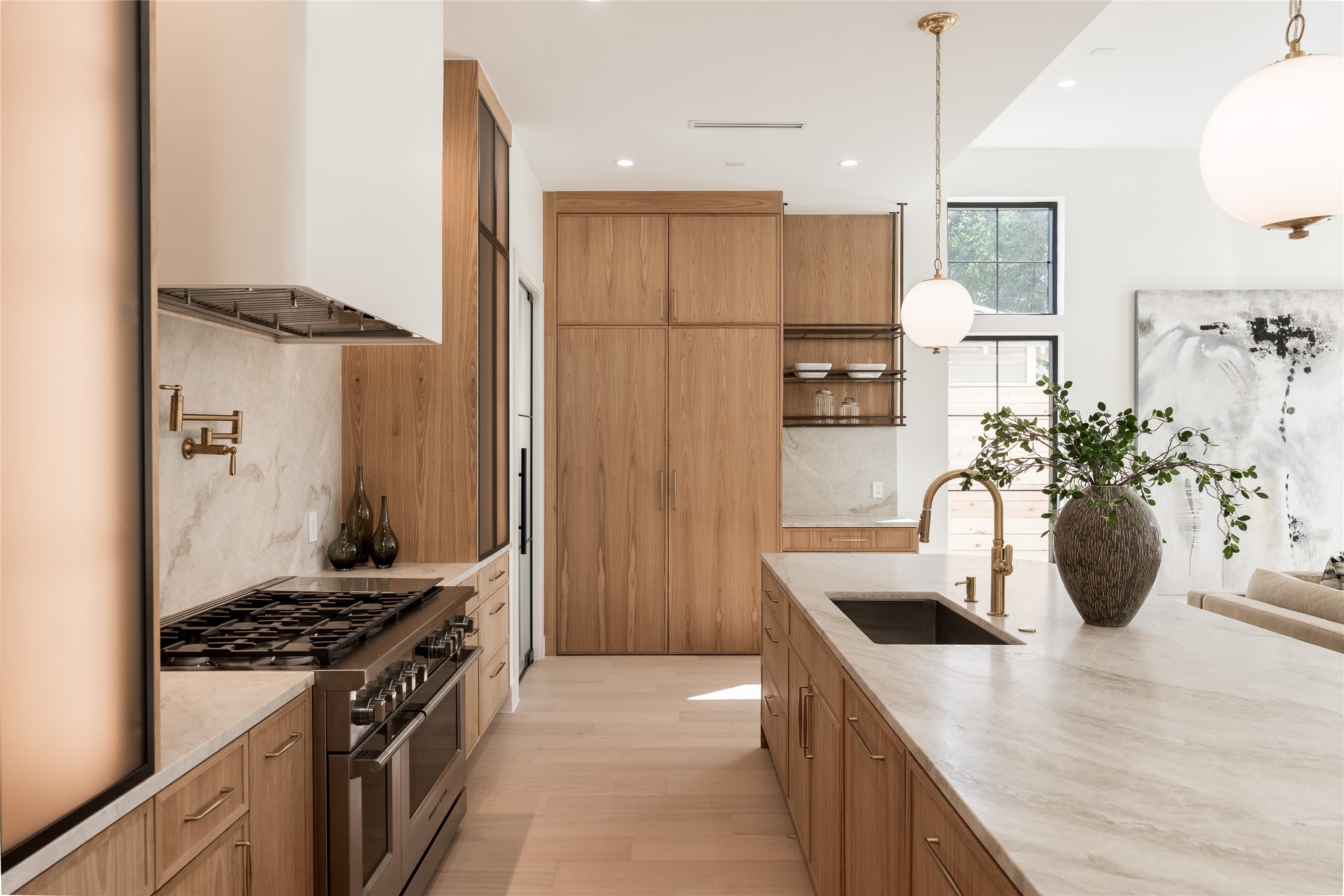 The chefs kitchen pairs custom white oak cabinetry with natural stone surfaces, while panel ready Fisher & Paykel refrigerator and freezer columns disappear seamlessly into the cabinetry.