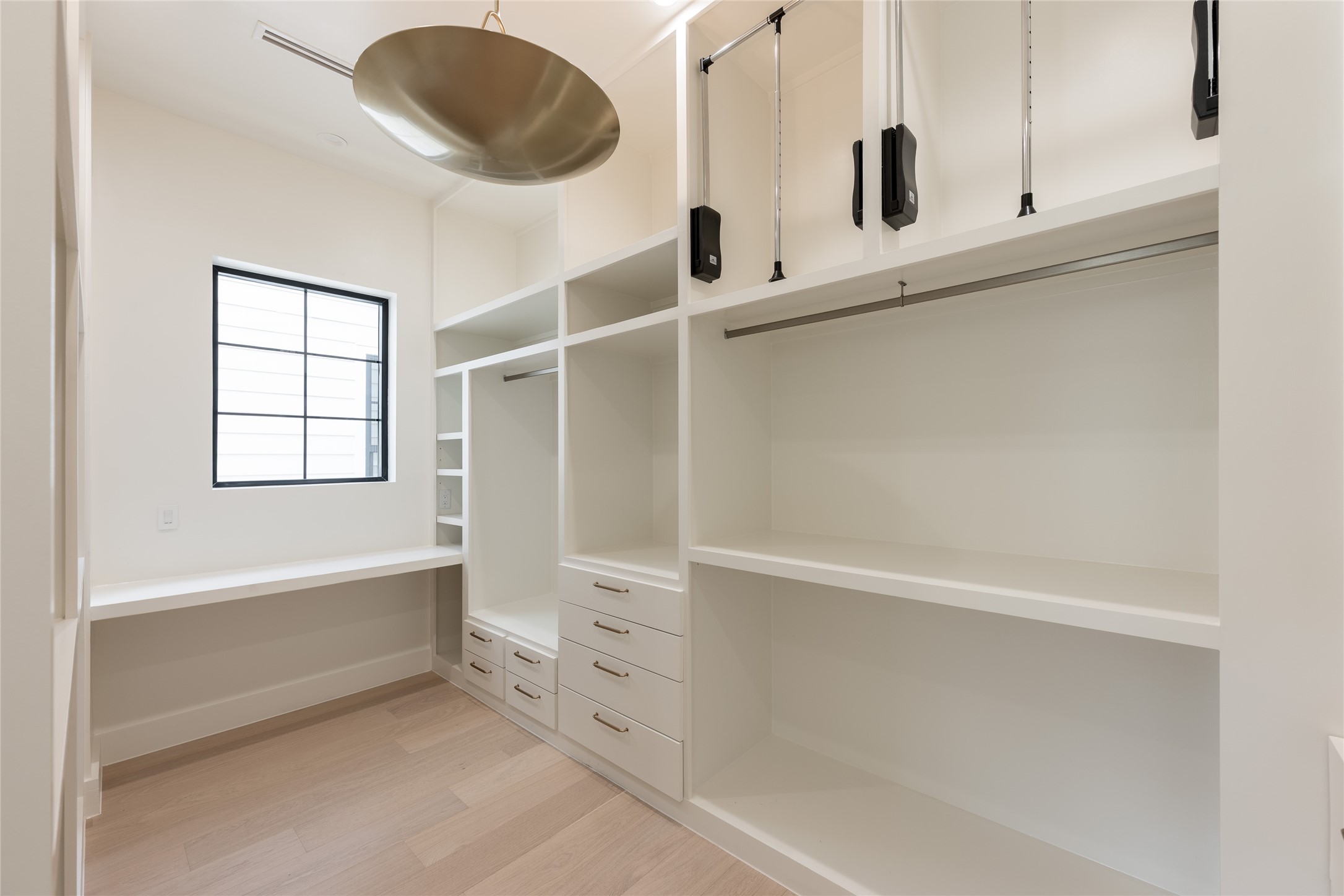 A second view of the primary closet highlights the generous proportions, with extensive custom shelving, hanging space and natural light creating a dressing area that feels open rather than simply utilitarian.