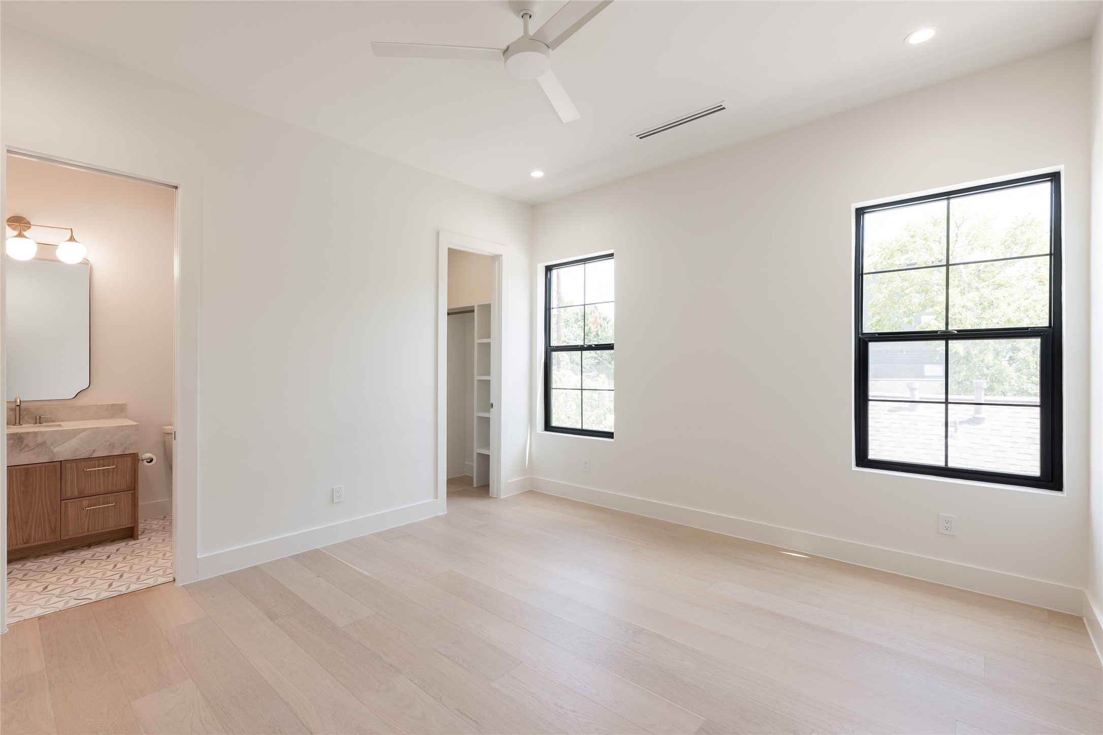 The secondary bedroom is generously scaled and filled with natural light, with direct access to its private ensuite bath creating a comfortable retreat for family or guests.
