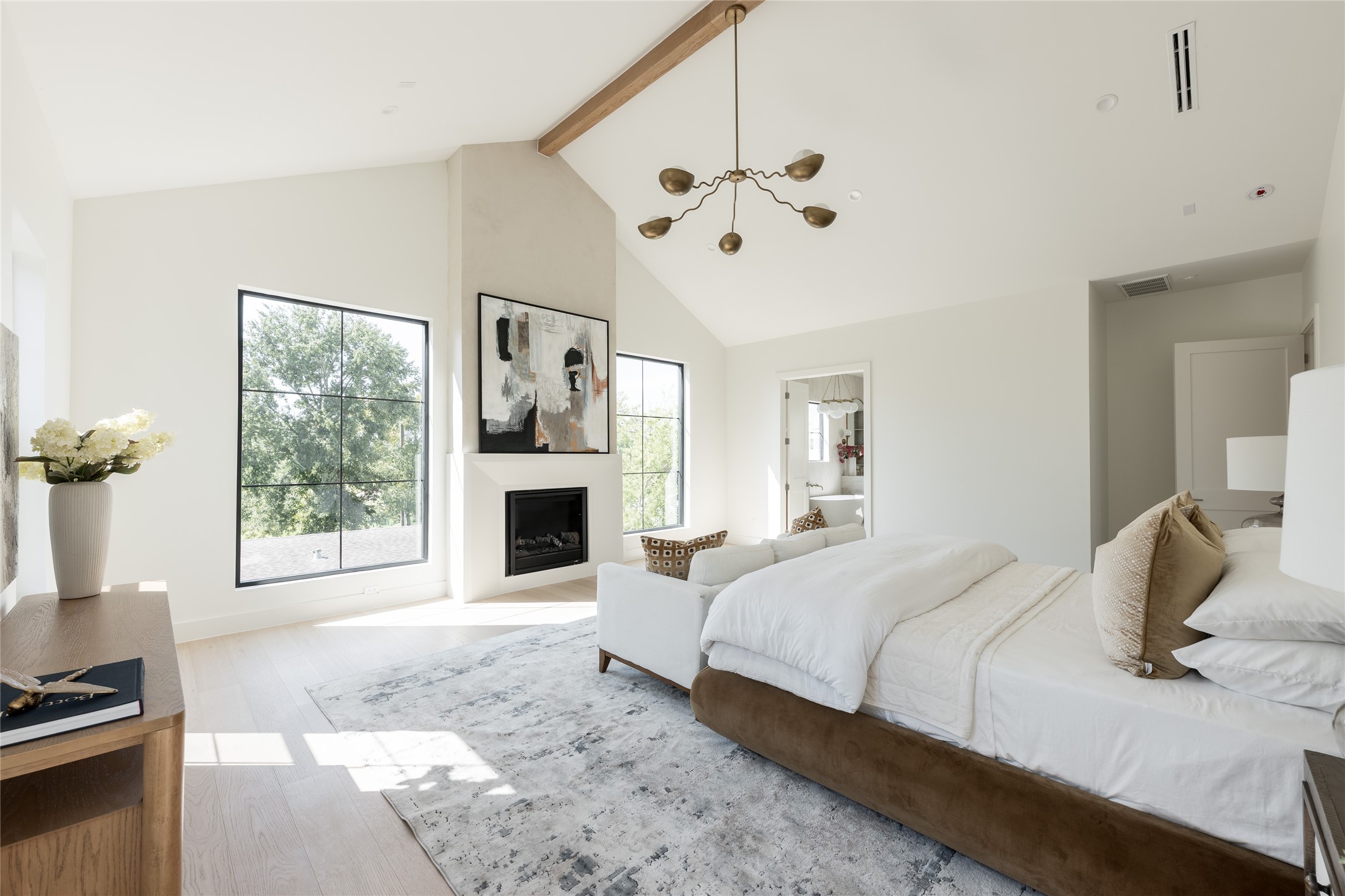 A first glimpse into the primary retreat, where dramatic ceiling heights meet understated sophistication. Natural light, warm wood accents, and a private sitting area establish a calming atmosphere, offering an early look at one of the home's most inviting spaces.