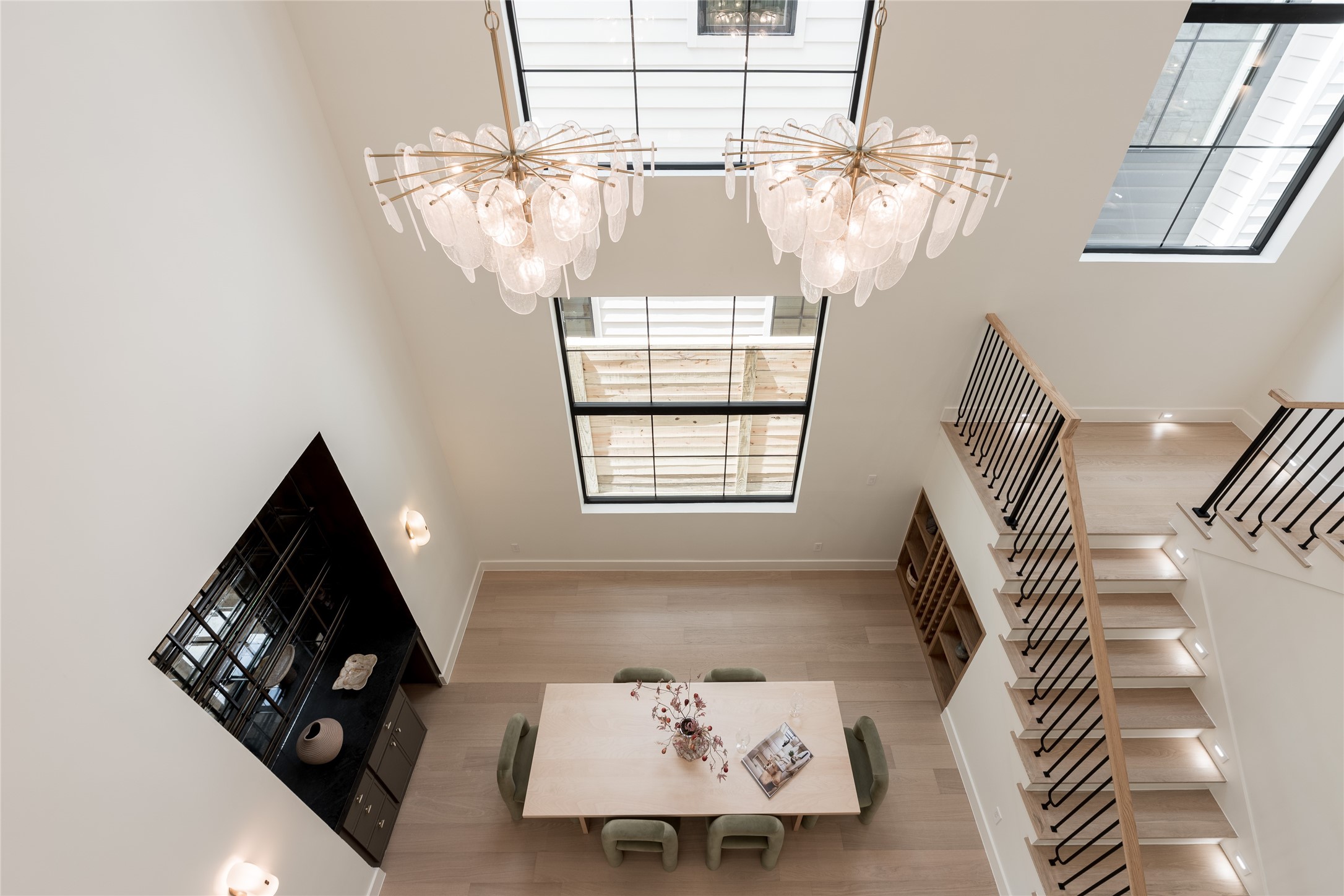 The two story dining room turns vertical volume into part of the experience, with soaring ceilings, elevated windows and an open staircase creating a dramatic setting for entertaining.