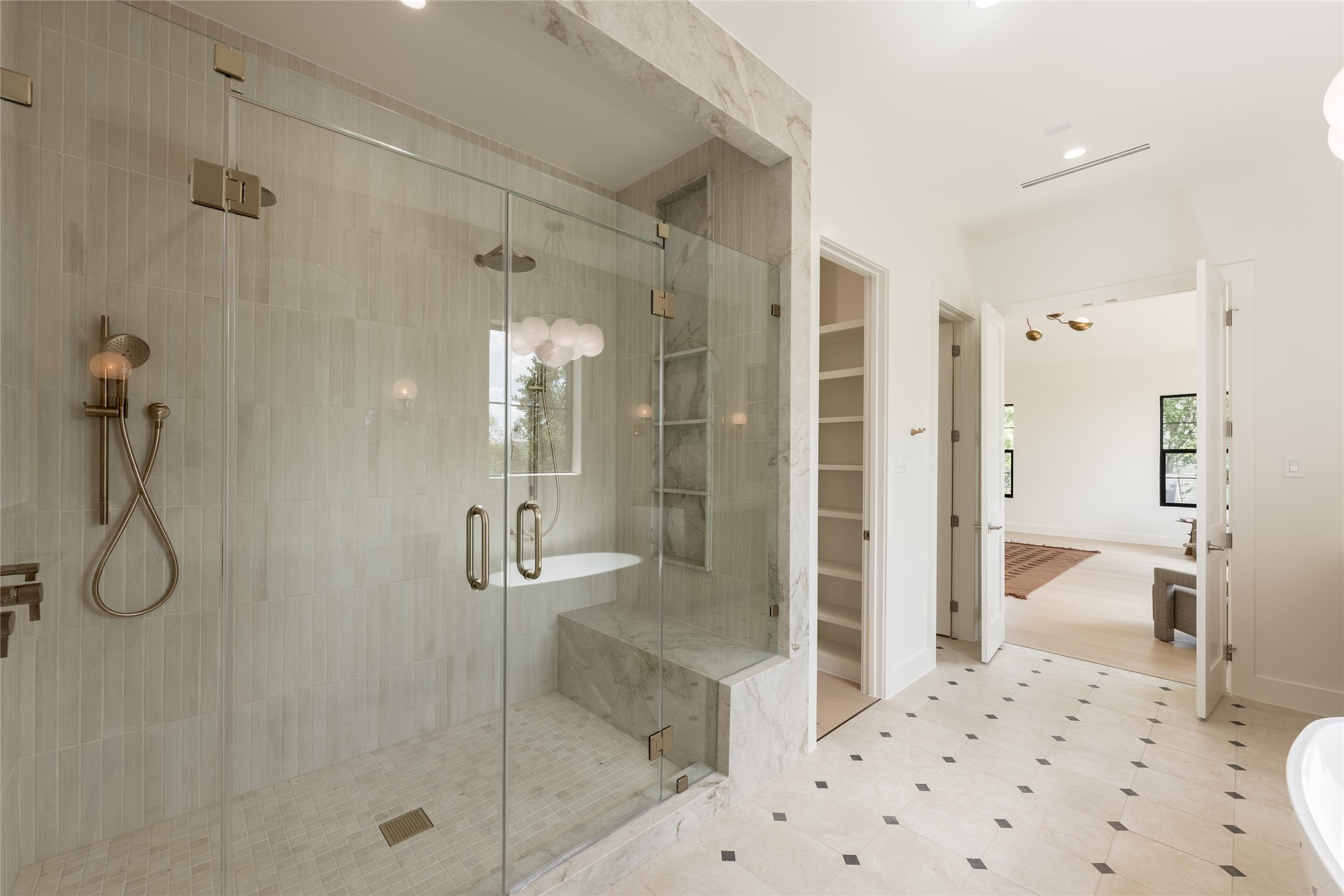 The oversized glass enclosed shower brings another layer of luxury to the primary bath, with full height designer tile and a built in bench creating a spa like experience at home.