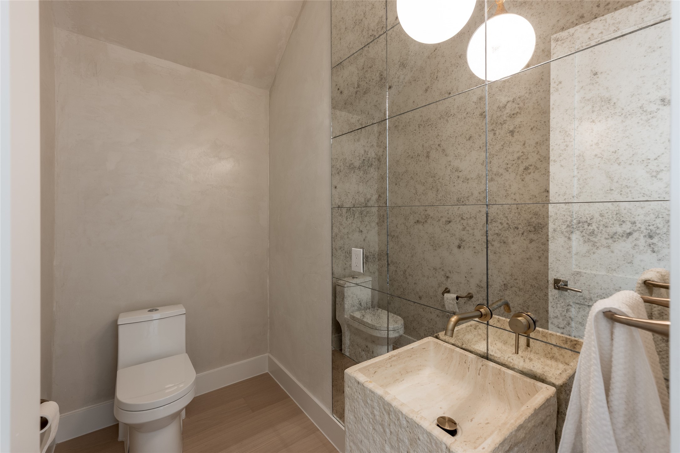 Antique mirror brings depth and character to the powder room along with plastered walls for an elevated feel.
