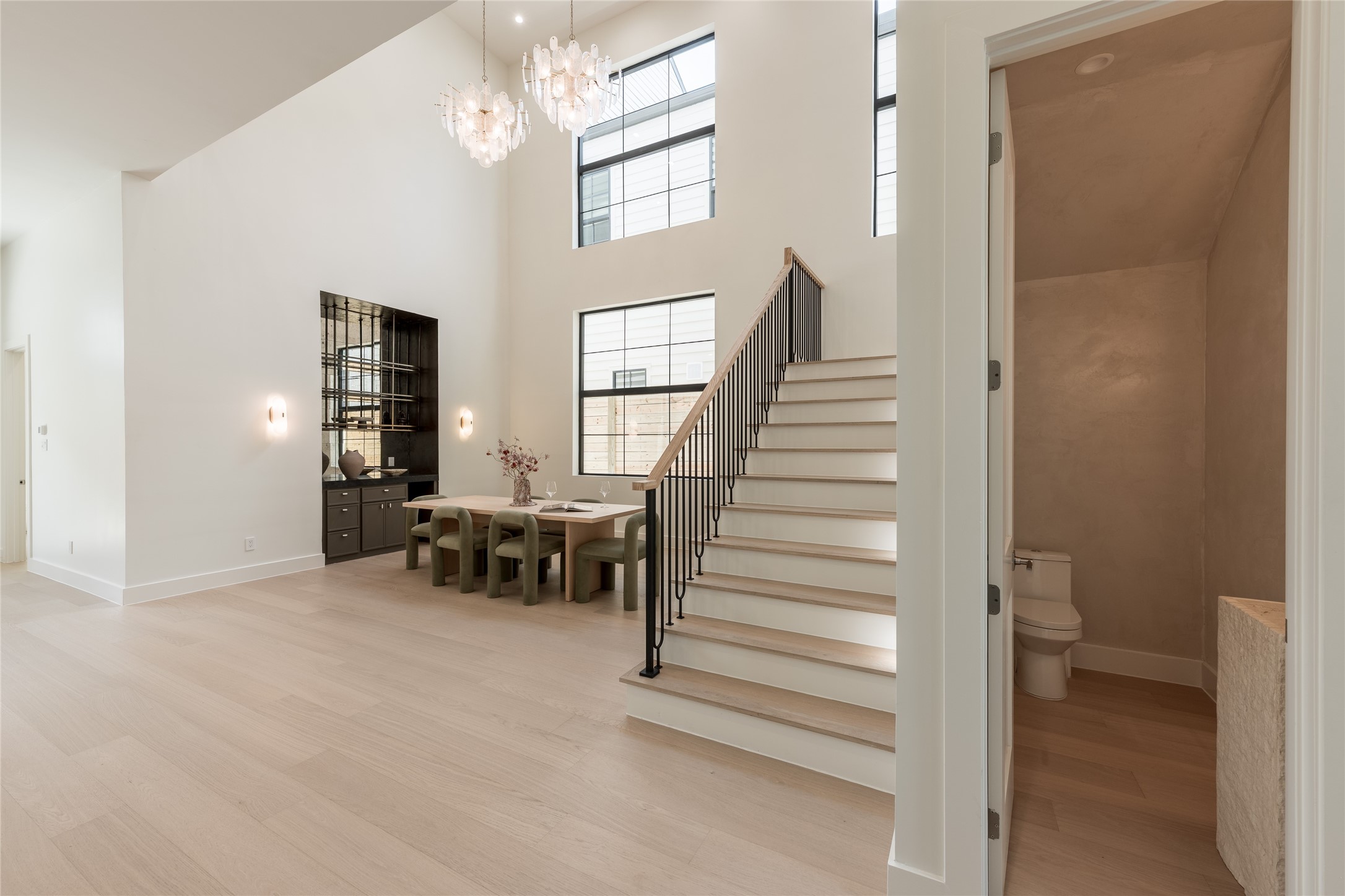 The two-story dining room makes a striking statement with soaring ceilings, cascading chandeliers, and expansive windows. An integrated bar adds sophistication, creating an inviting setting for intimate dinners and entertaining.