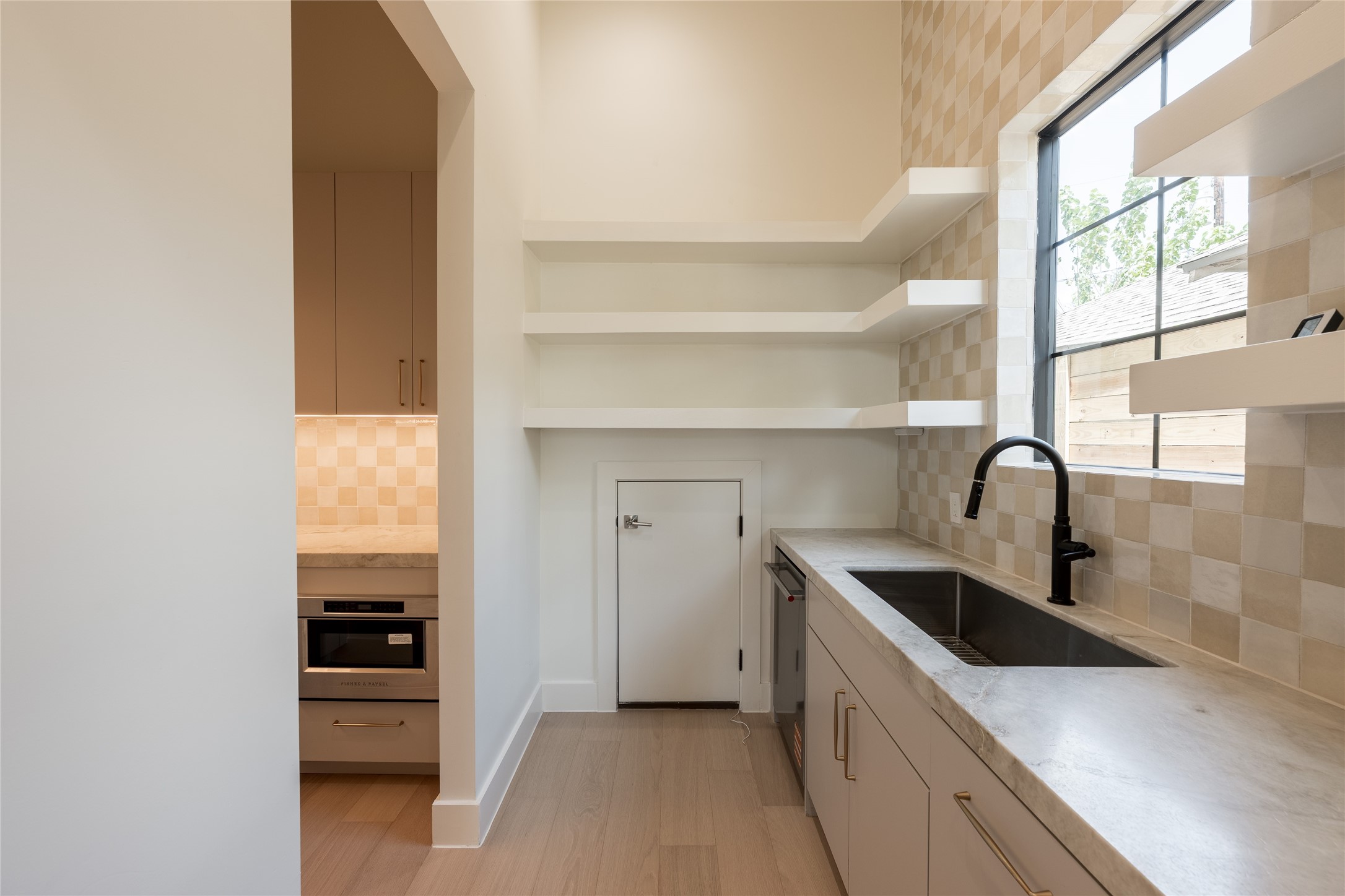 The scullery is designed for more than extra prep and storage, with a dedicated grocery pass through connecting directly from the garage for effortless unloading. Open shelving, natural stone counters and a secondary sink keep everyday function beautifully out of sight.