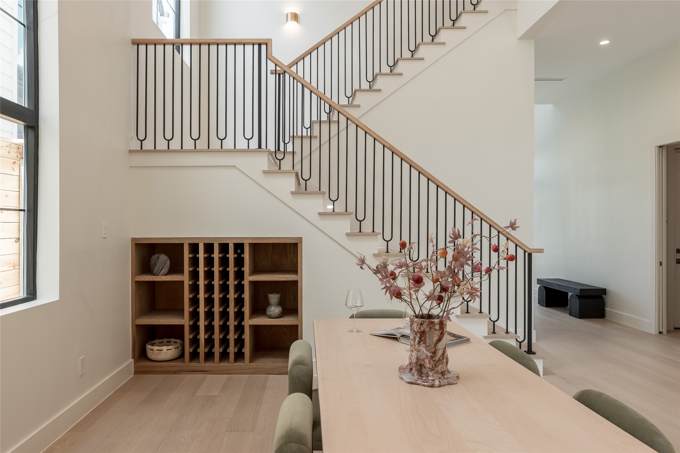 The custom oak staircase becomes an architectural centerpiece, with its modern railing system rising above the built in wine cove and adding definition to the dining rooms dramatic vertical scale.