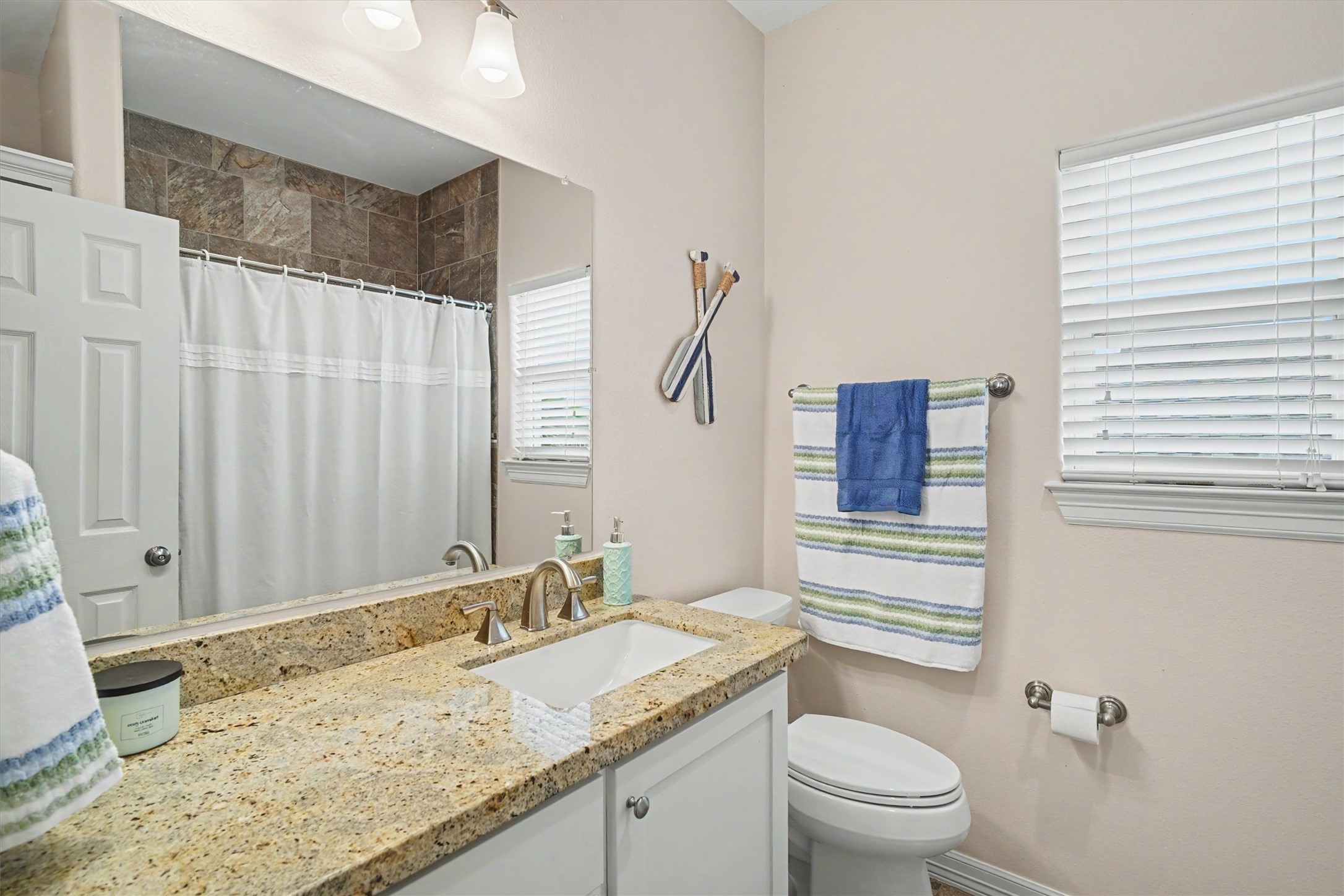 The guest bathroom carries the white cabinetry throughout the home. Granite countertops are an extra touch