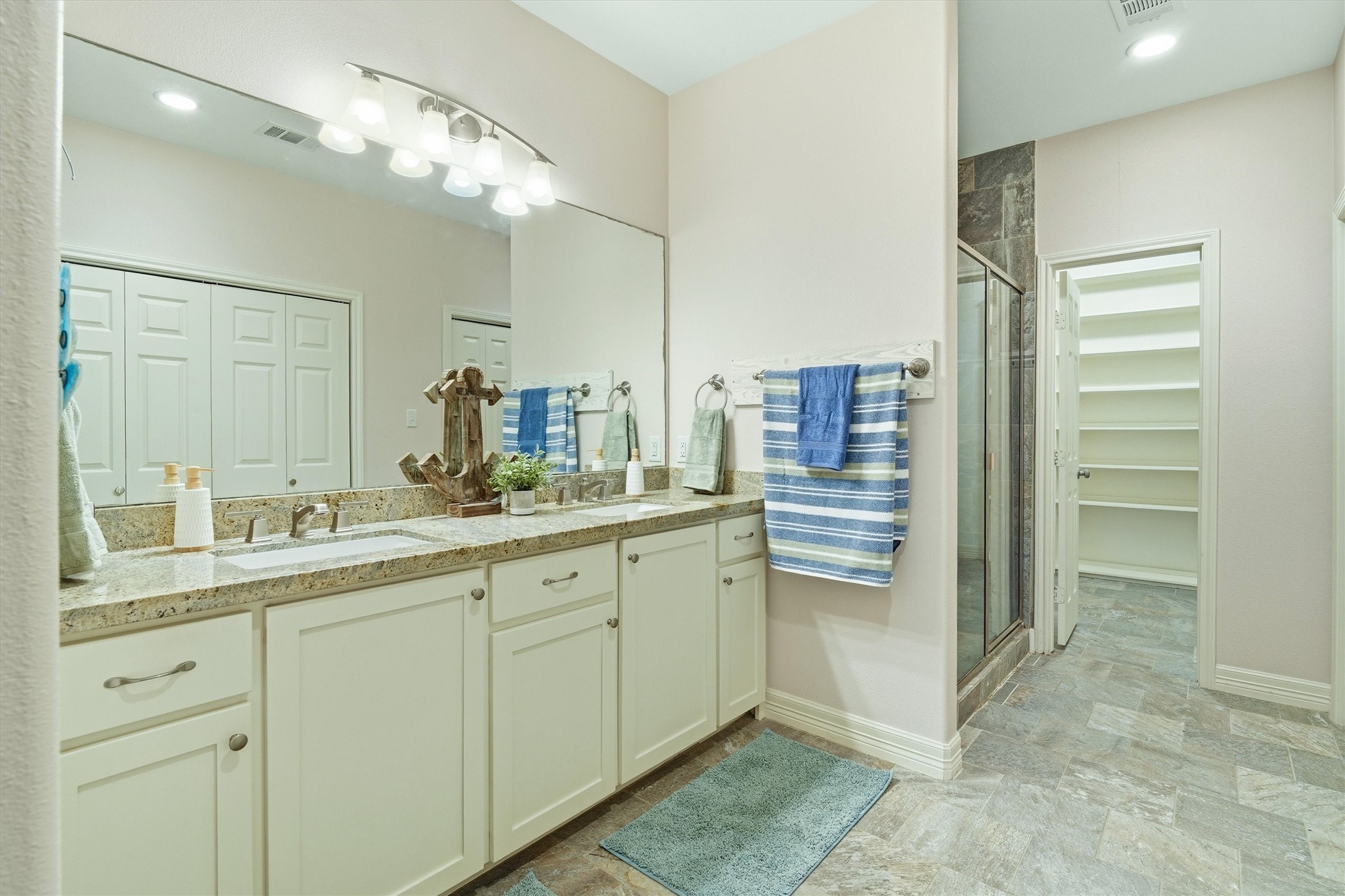 Oversized primary bathroom with double sinks, white cabinets and plenty of storage