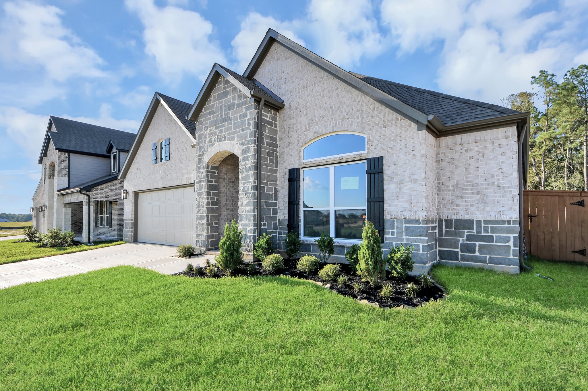 Meticulously maintained yard and lush landscape, paired with a premium elevation featuring captivating brick accents. Modern coach lights add a touch of contemporary elegance to the exterior.