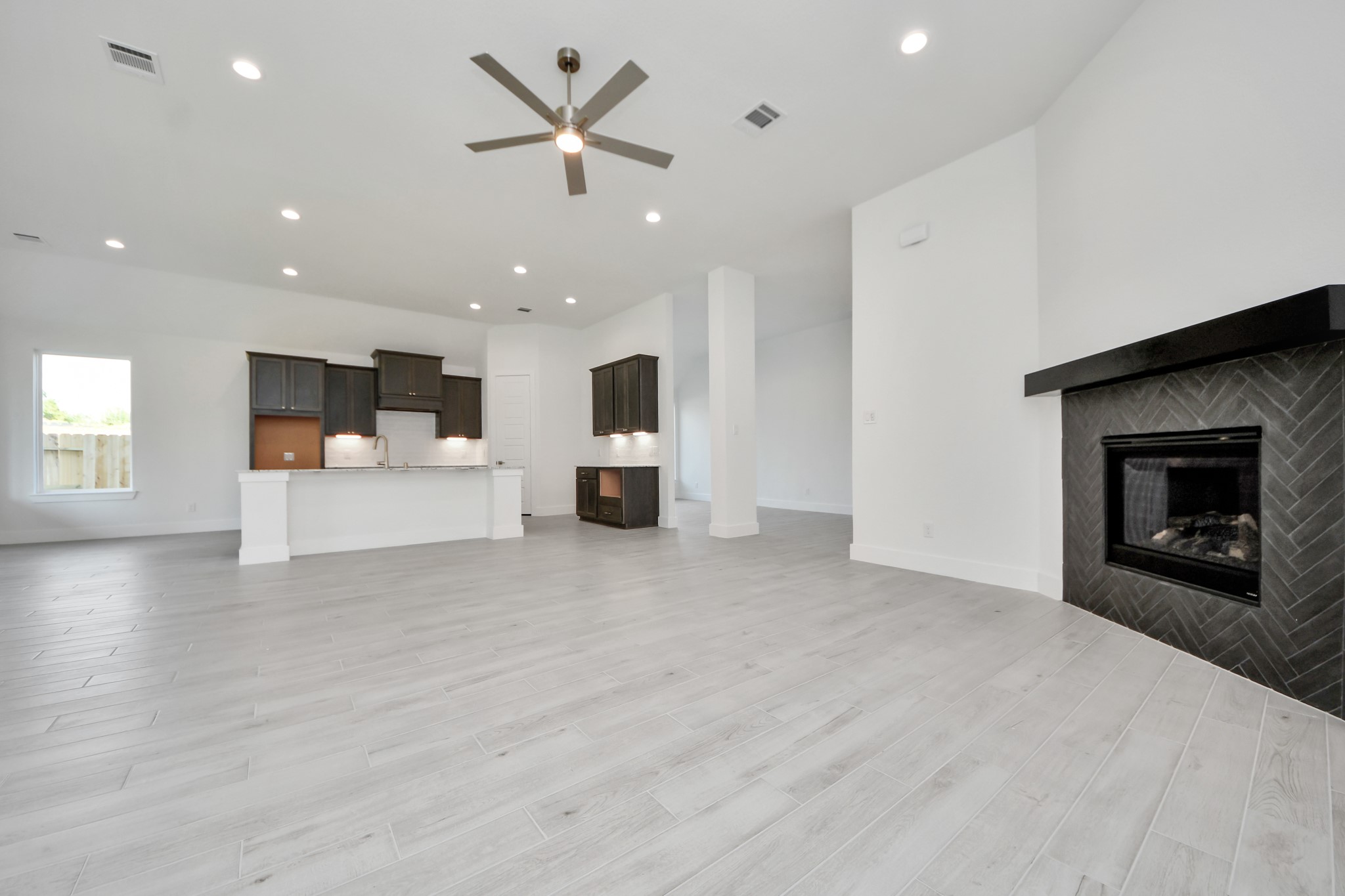 Relax and unwind in this inviting family room, illuminated by abundant natural light streaming in through tall windows, complemented by high ceilings and stunning flooring. Stay comfortable year-round with the gentle breeze from the ceiling fan, creating the perfect atmosphere for family gatherings.