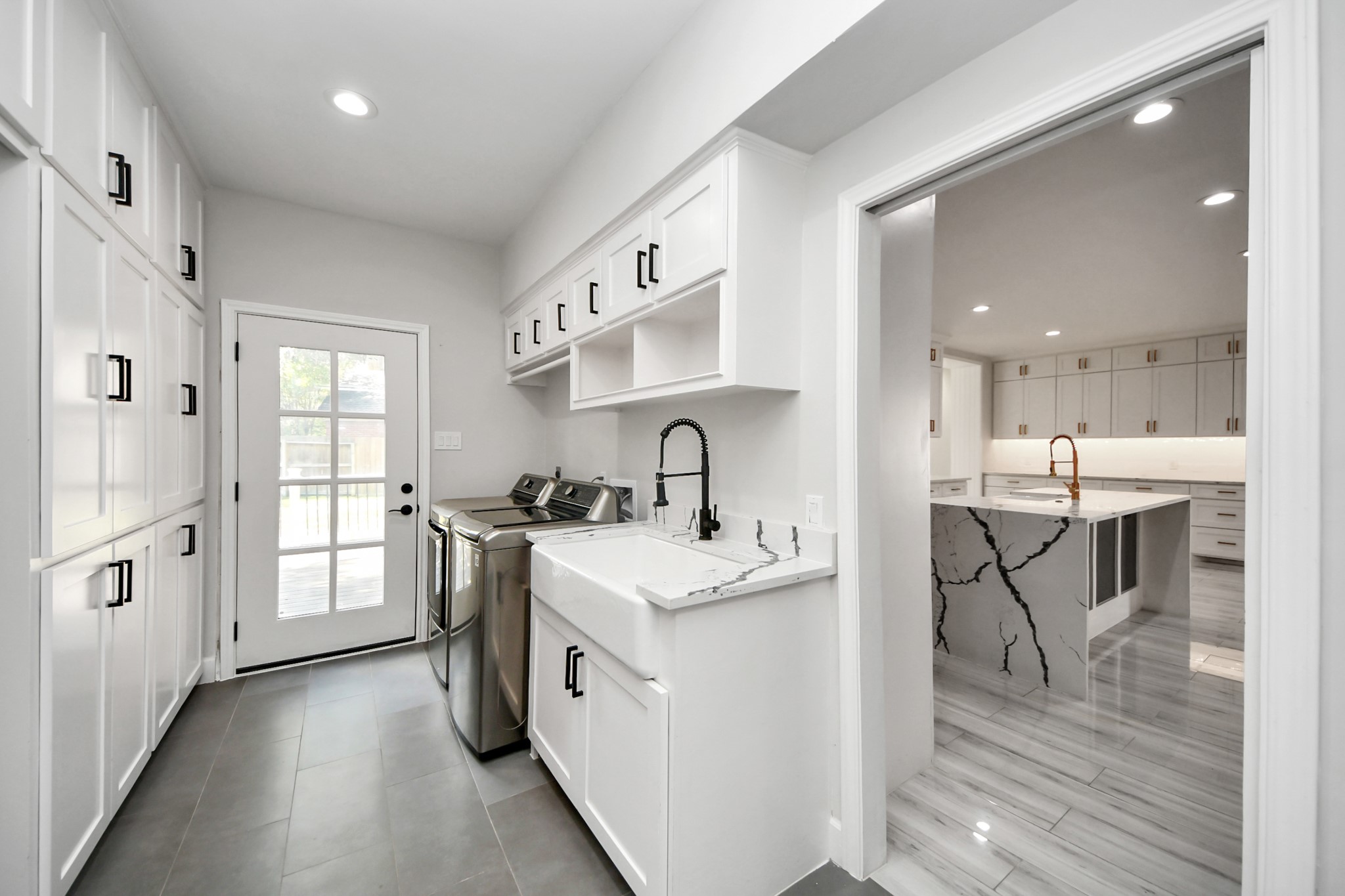 Laundry/utility room with abundant storage, full-size washer and dryer, and a farmhouse sink.