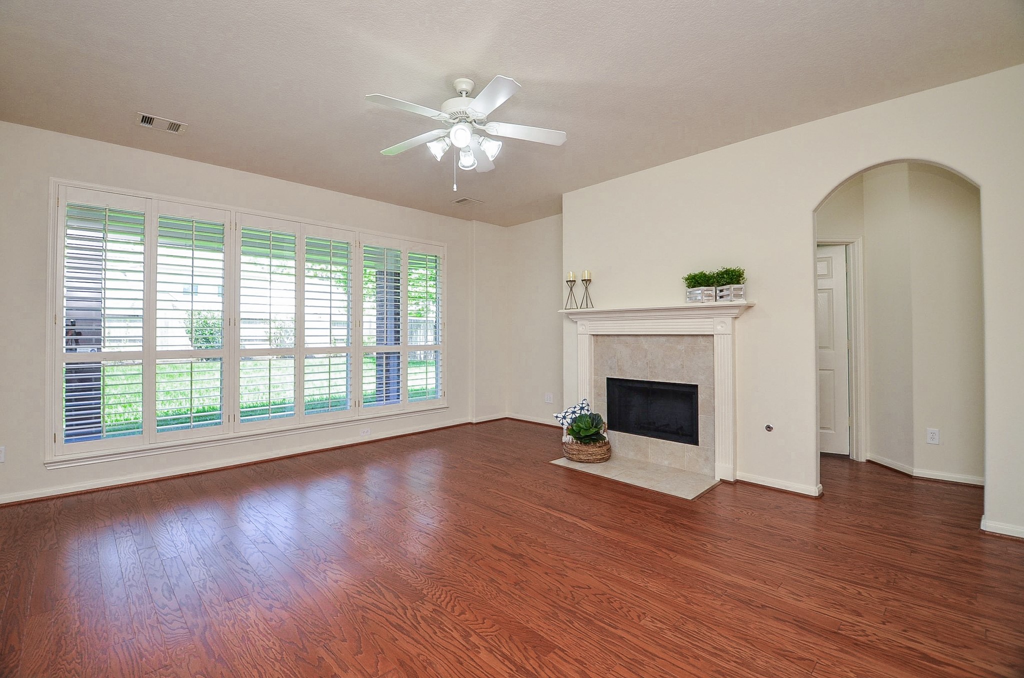 Abundant sunlight fills this inviting family room, highlighting elegant wood flooring and offering seamless access to the kitchen.