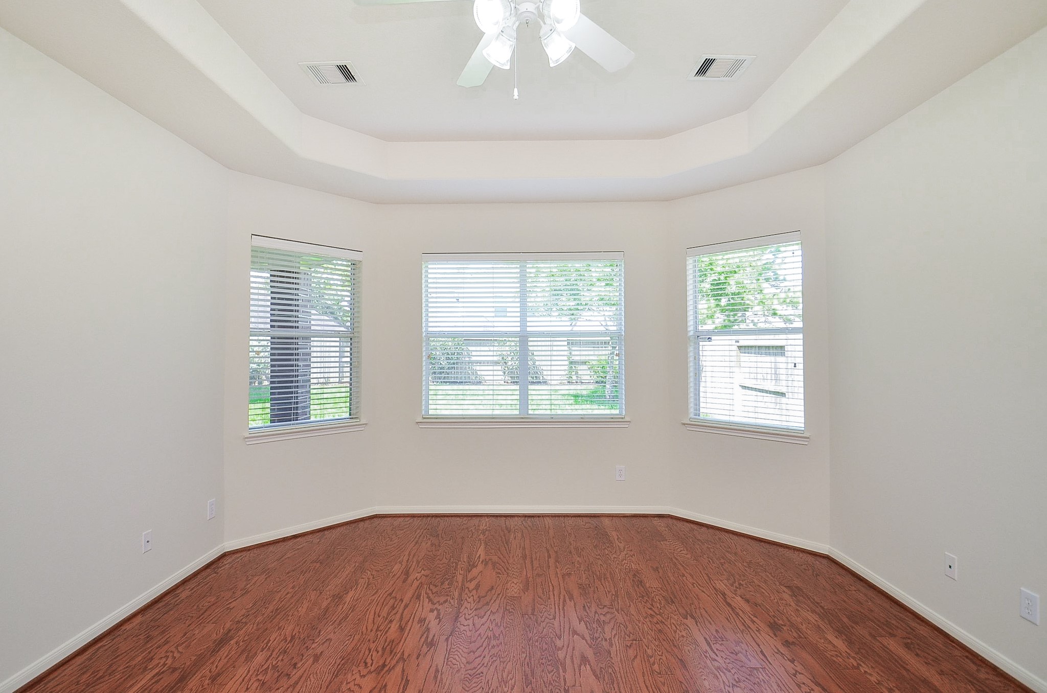 Experience the elegance of primary room, featuring a grand entrance with a stunning arched window and tray ceiling, welcoming you with warmth and style.