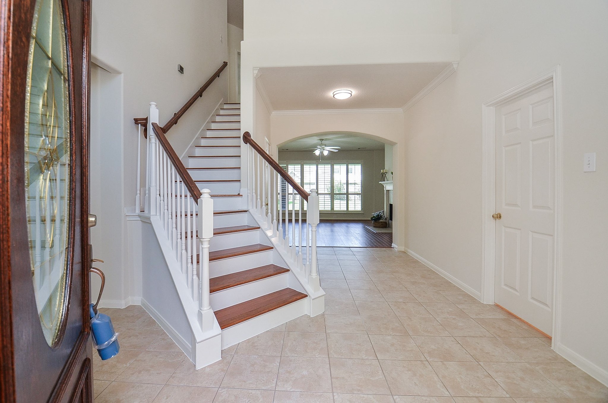 Experience elegance with a high ceiling entryway leading to a spacious living area, featuring warm wood floors and a cozy fireplace, perfect for entertaining.