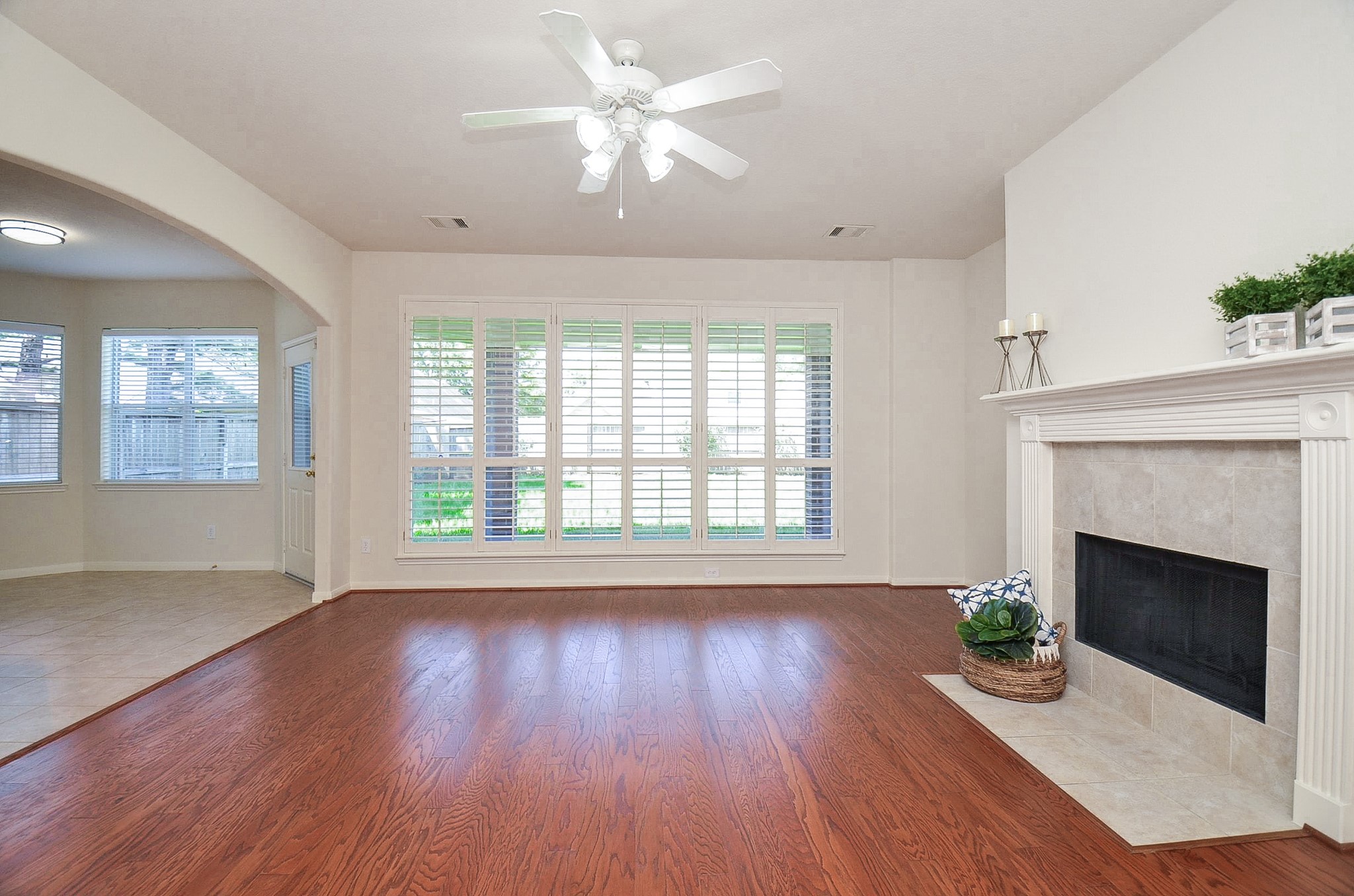 Abundant sunlight fills this inviting family room, highlighting elegant wood flooring and offering seamless access to the kitchen.