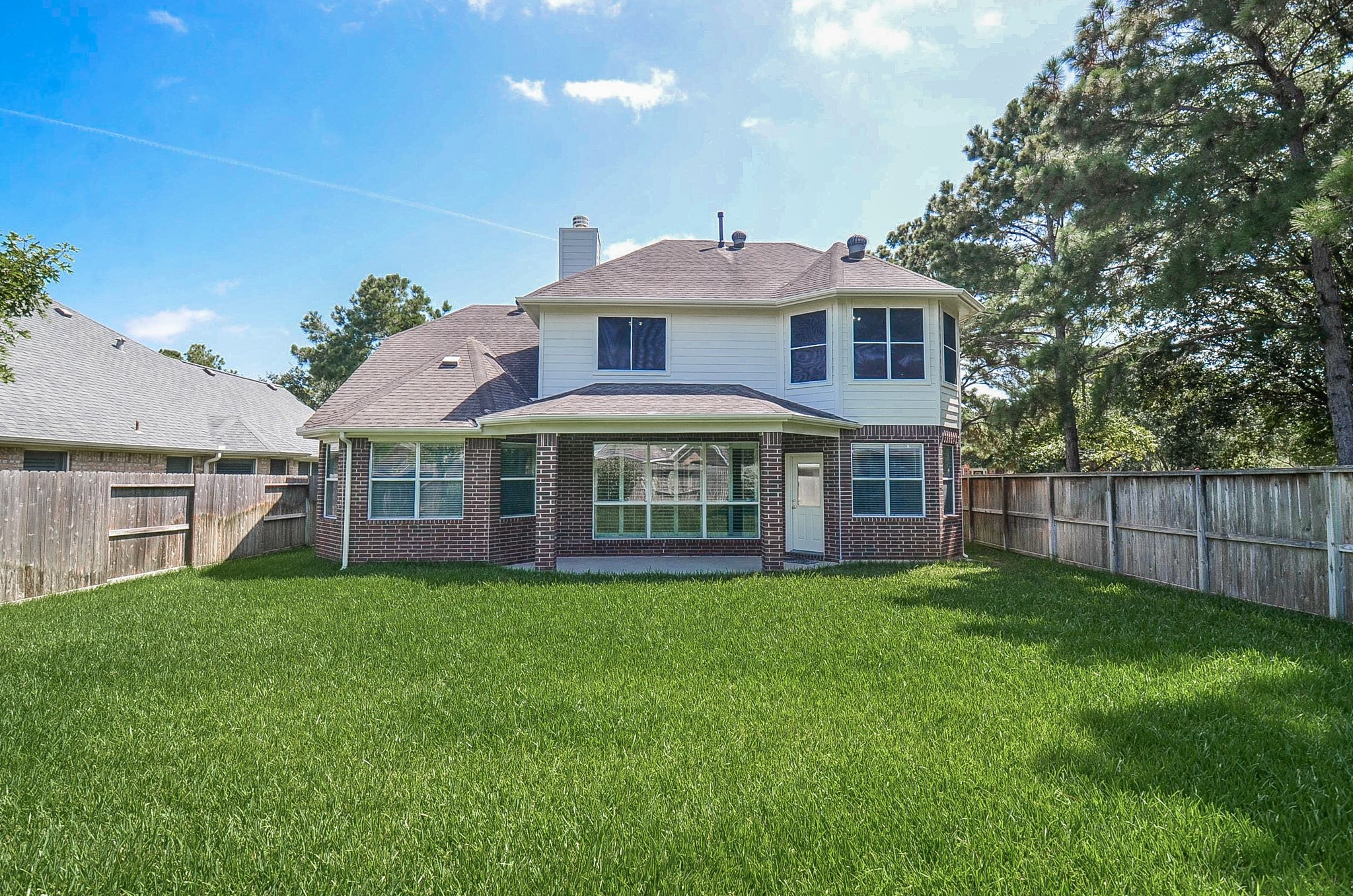 Spacious home nestled on a large, lush lot with mature trees and a fenced backyard, offering ample privacy and outdoor space.