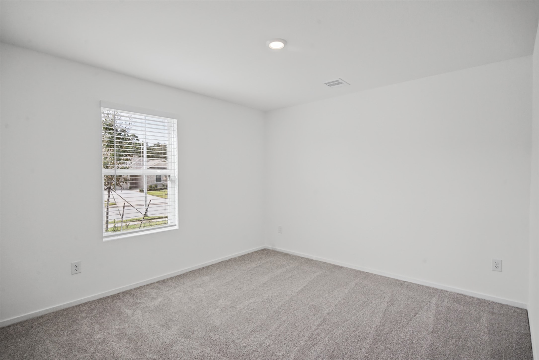 A bright, inviting bedroom with soft carpeting and natural lightan easy space to personalize as a comfortable bedroom, guest retreat, or home office.