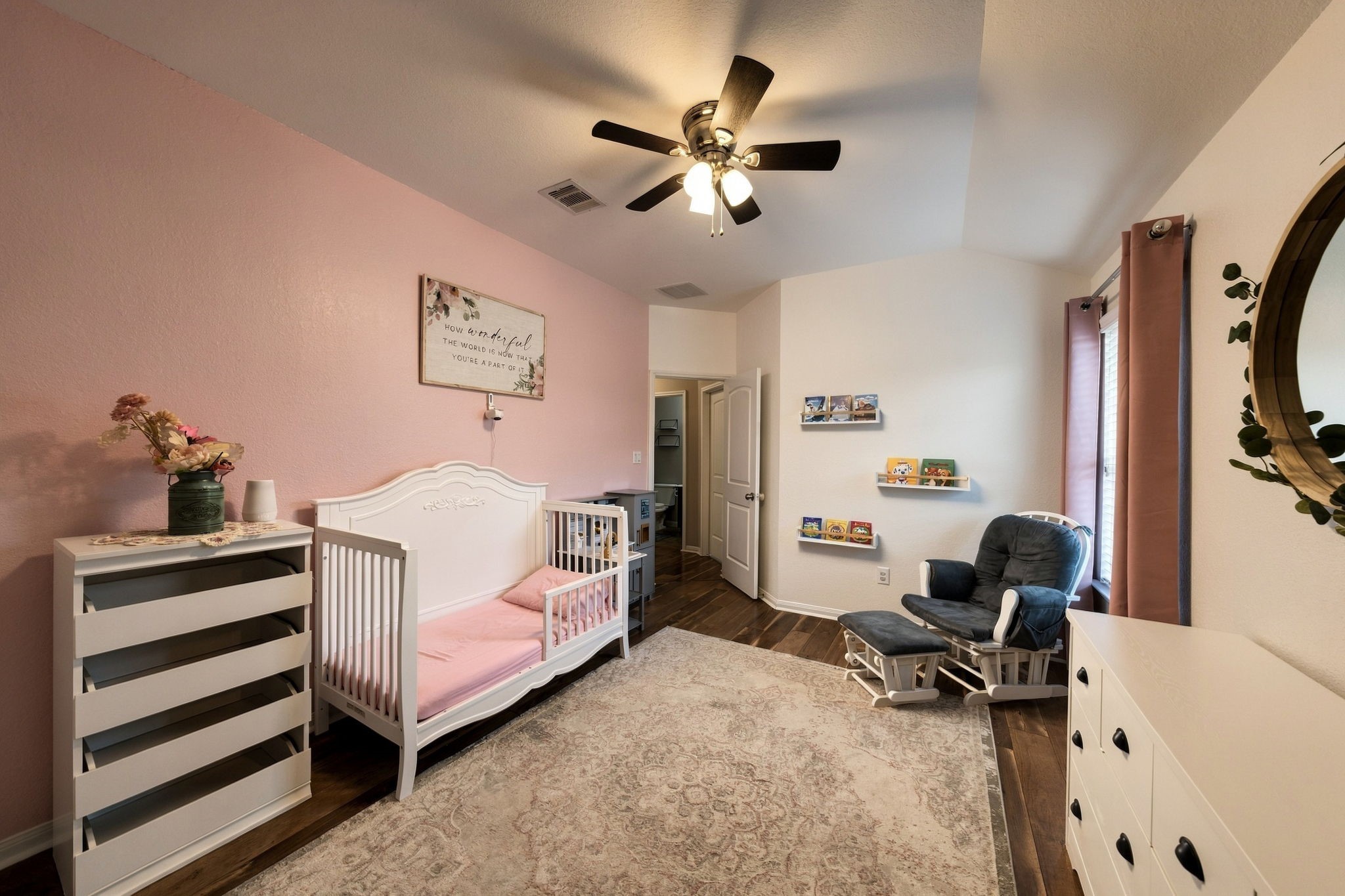 Charming nursery with a soft pink accent wall.