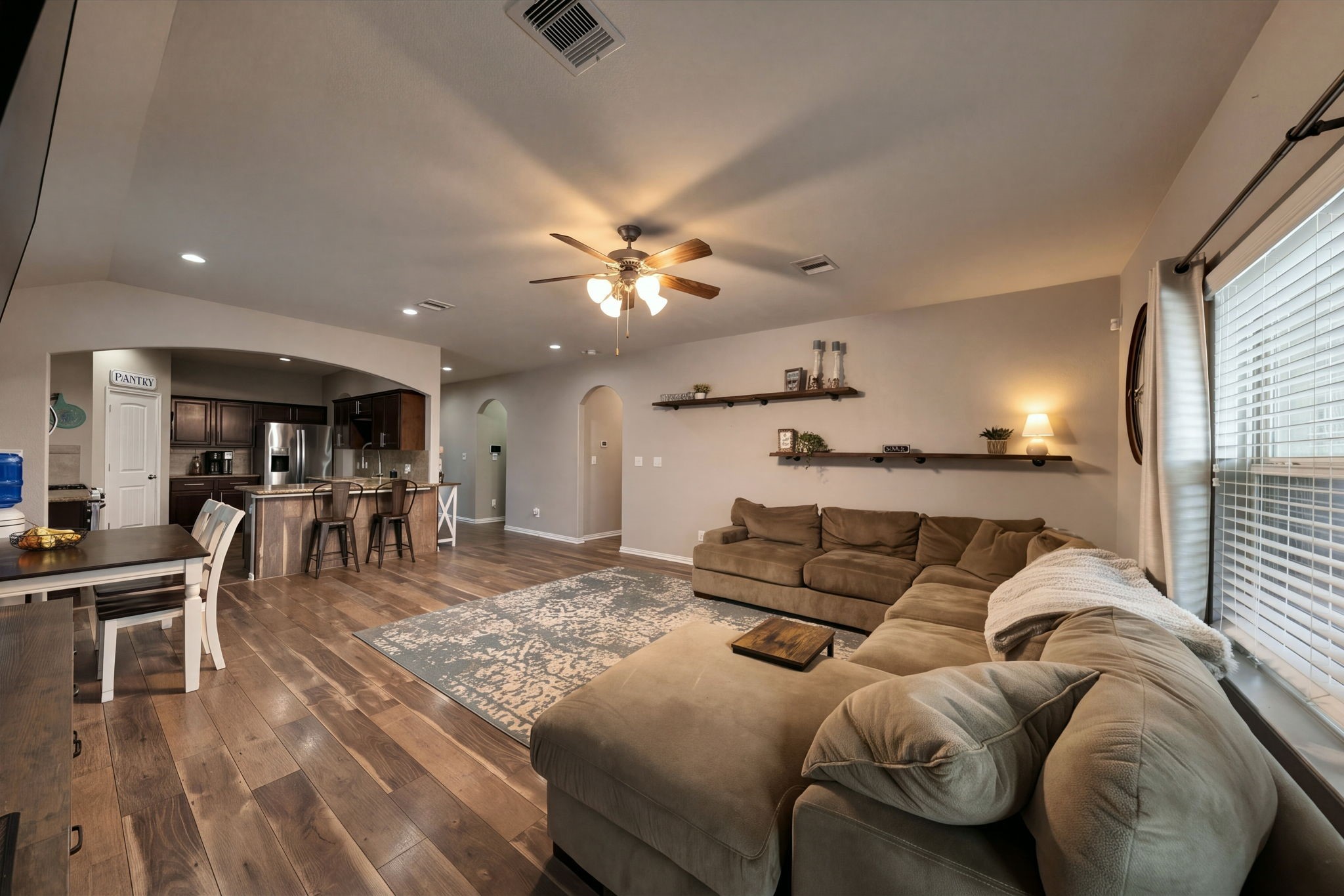 Spacious open-concept living area with warm wood flooring, a convenient breakfast bar. Natural light filters in through large windows, creating an inviting atmosphere. Spacious open-concept living area with warm wood flooring, a convenient breakfast bar. Natural light filters in through large windows, creating an inviting atmosphere.