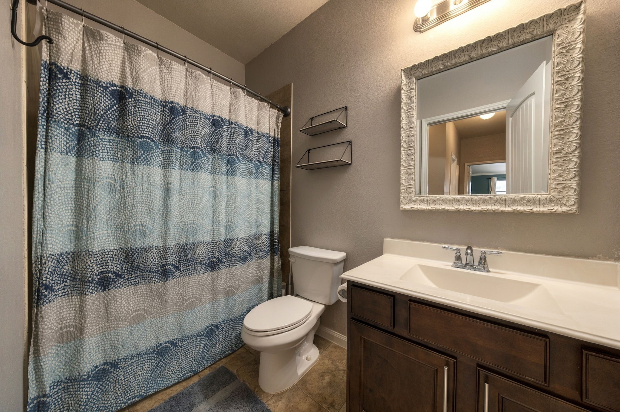 Charming bathroom featuring elegant vanity with a large ornate mirror, and contemporary lighting.