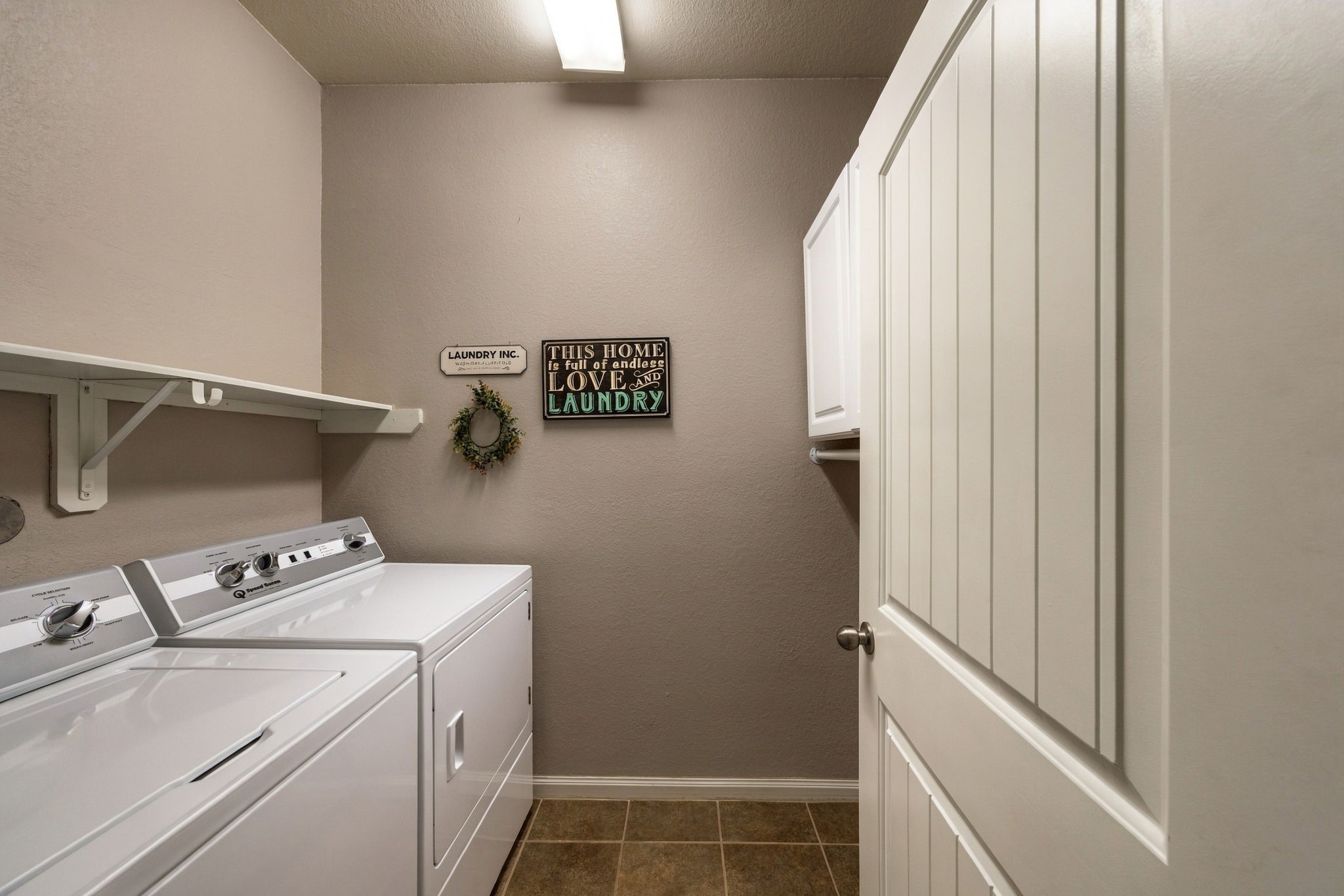 Bright and functional laundry room featuring modern appliances, ample shelving, and stylish decor.