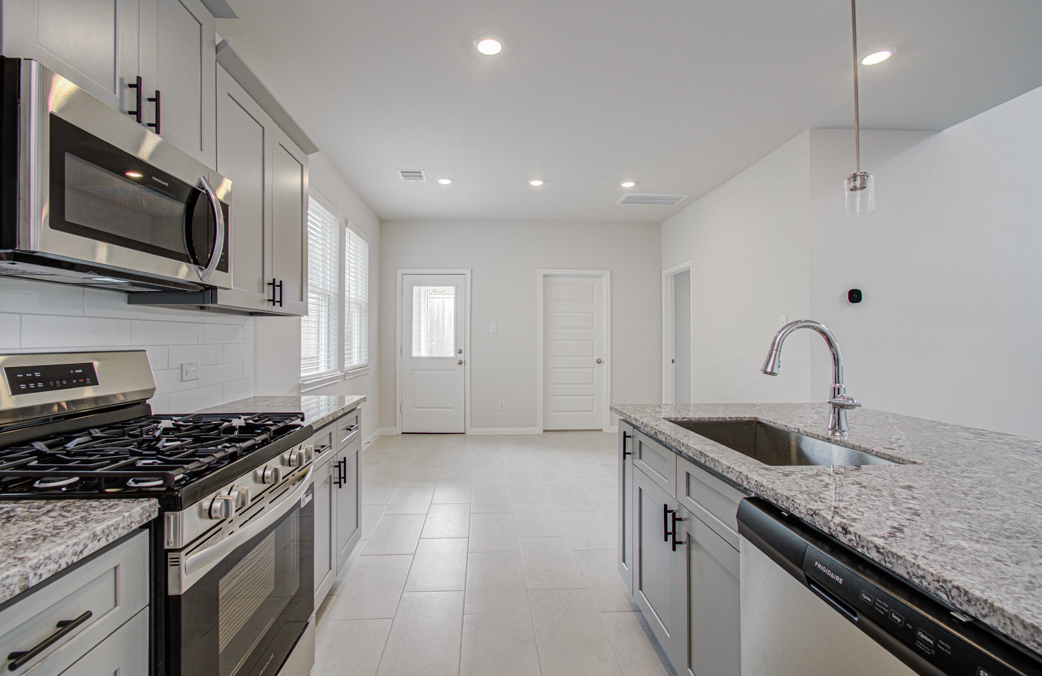 Modern kitchen with sleek stainless steel appliances, granite countertops, and ample natural light, offering a bright and inviting space for cooking and entertaining. Please Note this is a different home/floorplan in the community.