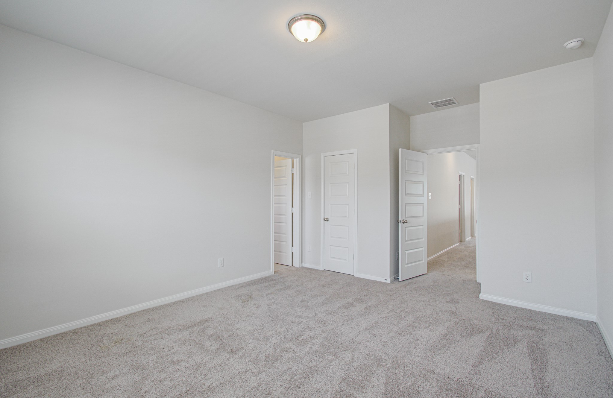 Spacious secondary suite bedroom with plush carpeting, soft neutral walls, and ample natural light, featuring dual door . Please Note this is a different home/floorplan in the community.