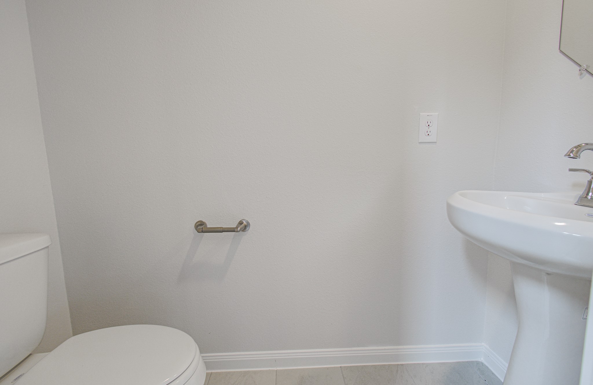Bright and clean half-bath located downstairs featuring a pedestal sink and modern fixtures. Please Note this is a different home/floorplan in the community.