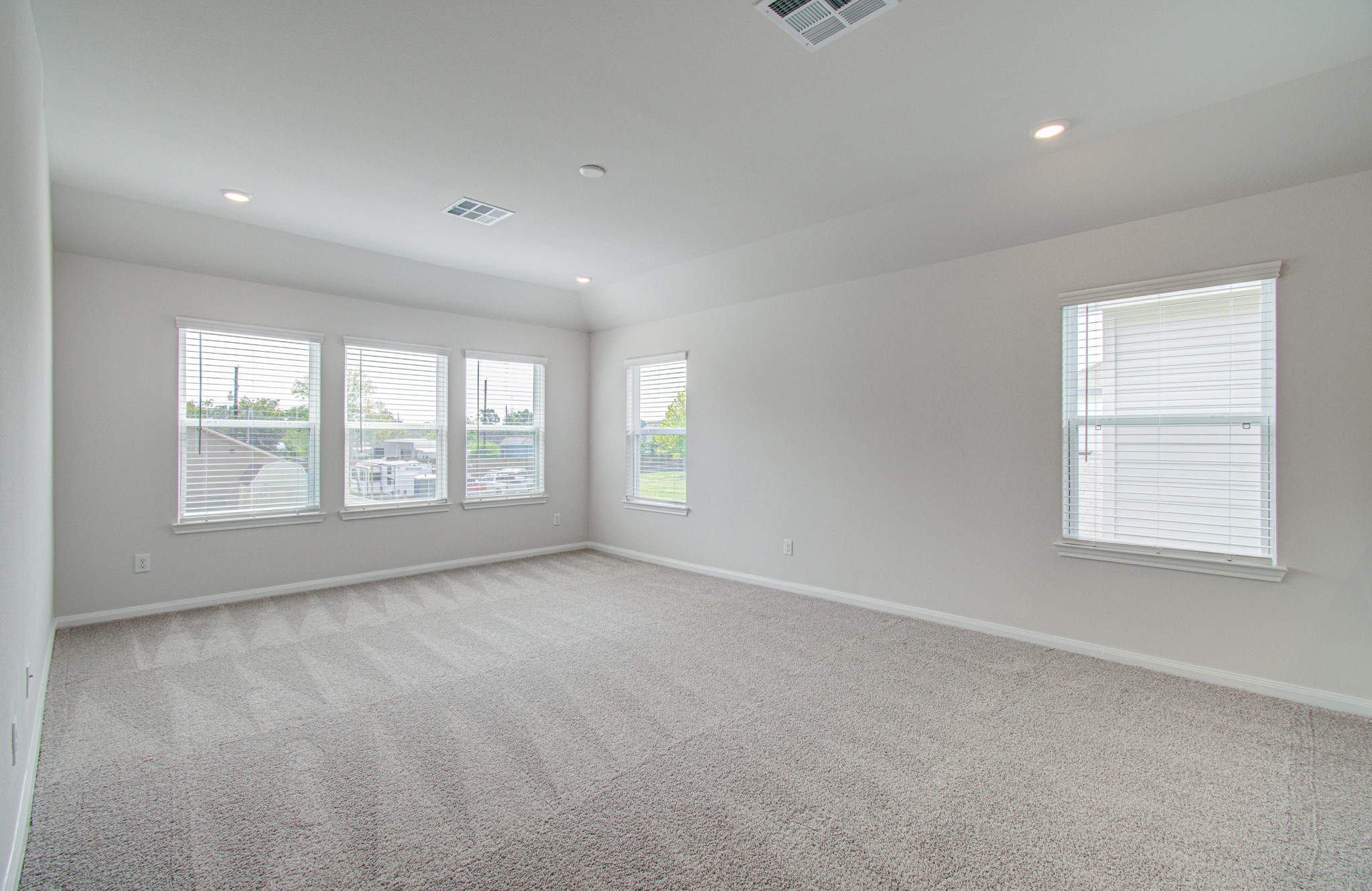 Spacious and bright room with large windows, soft carpeting, and recessed lighting, offering a comfortable and inviting living area. Please Note this is a different home/floorplan in the community.