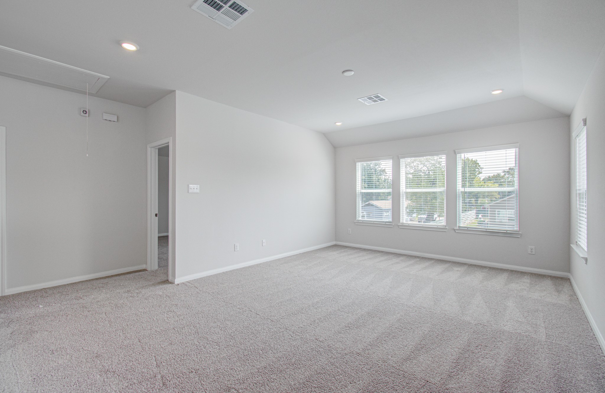 Spacious, light-filled room with large windows, plush carpeting, and a neutral color palette, perfect for versatile living. Please Note this is a different home/floorplan in the community.