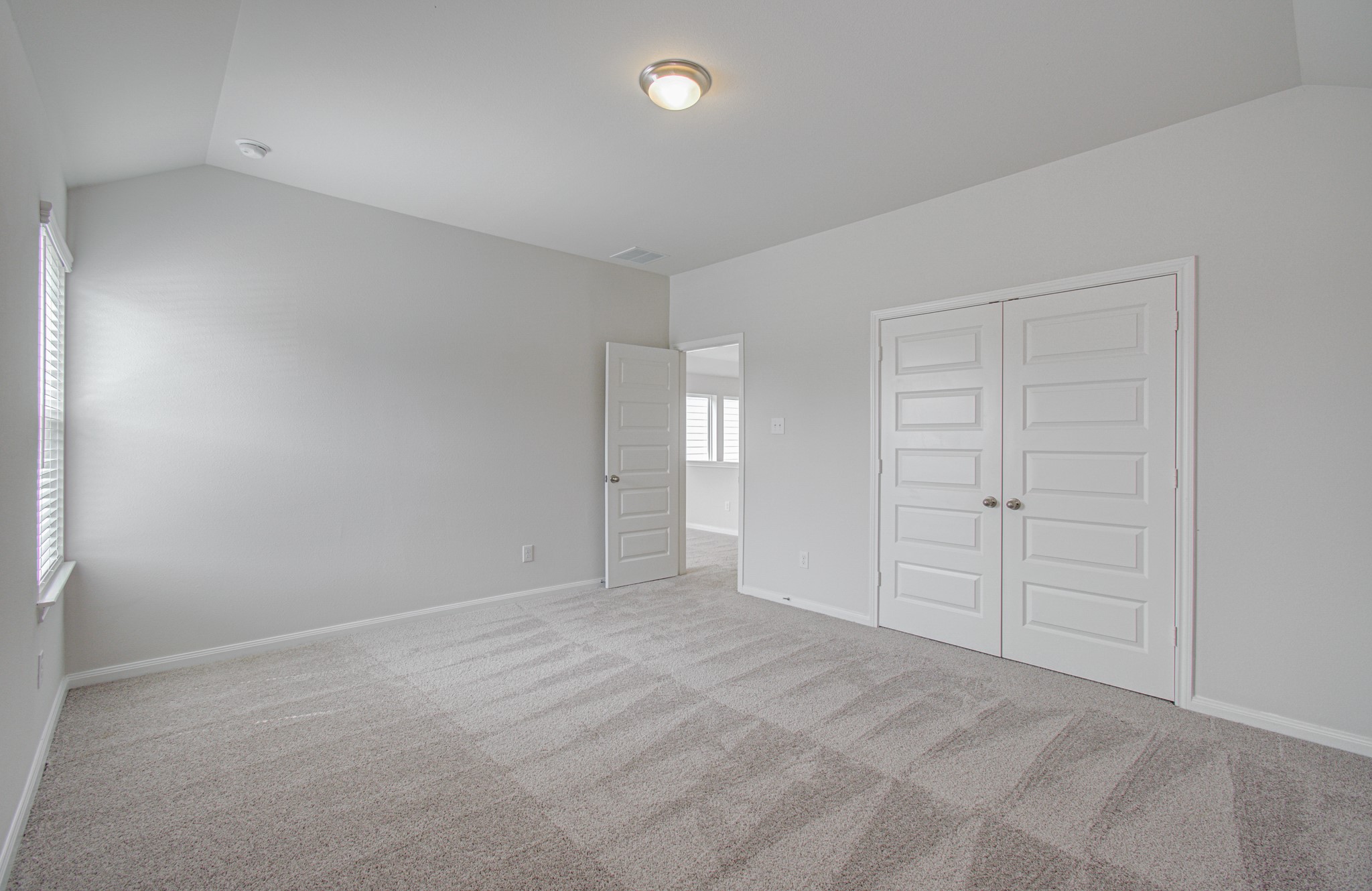Spacious third bedroom with plush carpeting, ample natural light from large windows, and dual-door closet for convenient storage. Please Note this is a different home/floorplan in the community.