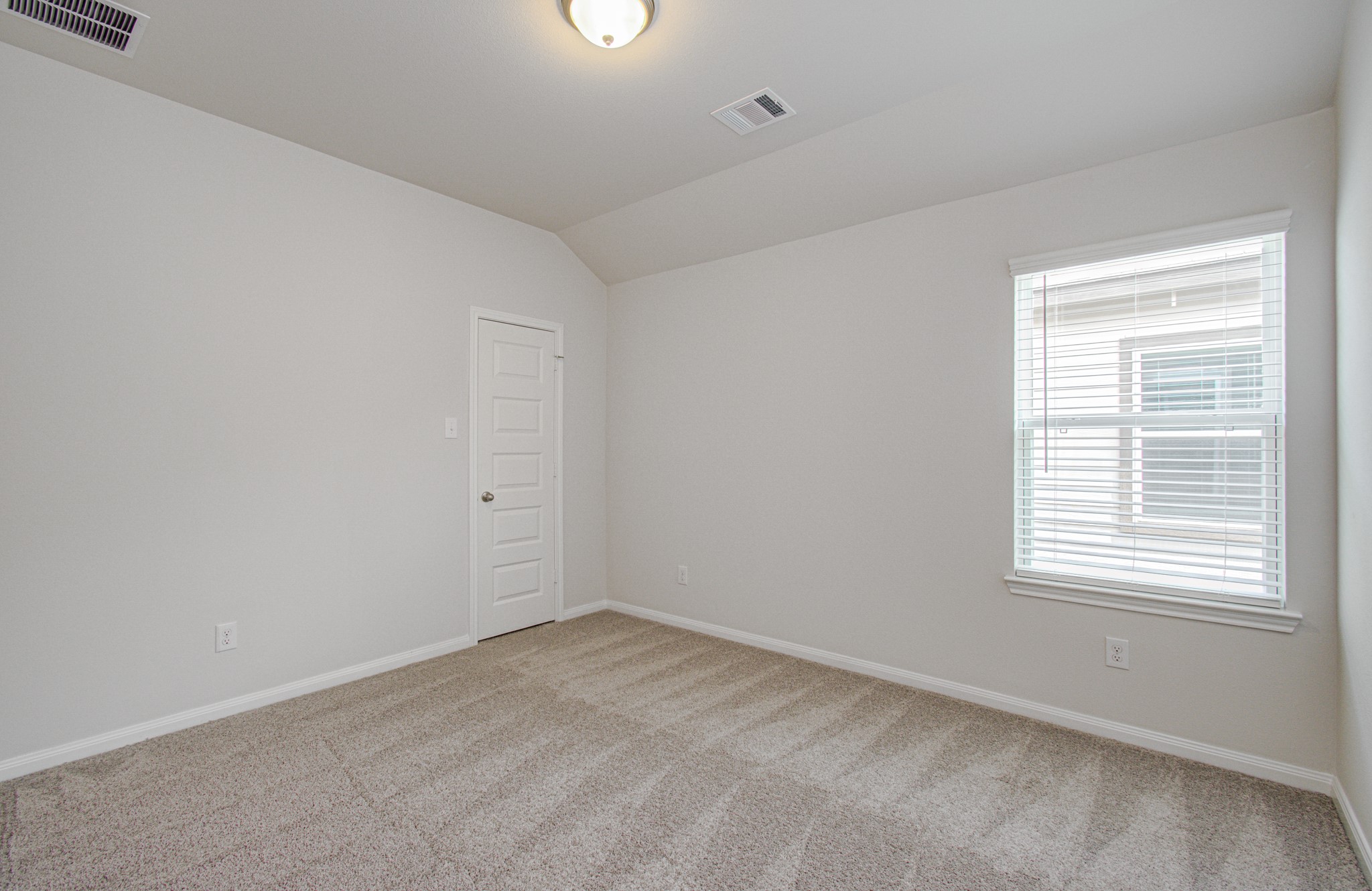 Bright, cozy fourth room with soft carpet flooring, neutral walls, and ample natural light from a large window. Please Note this is a different home/floorplan in the community.