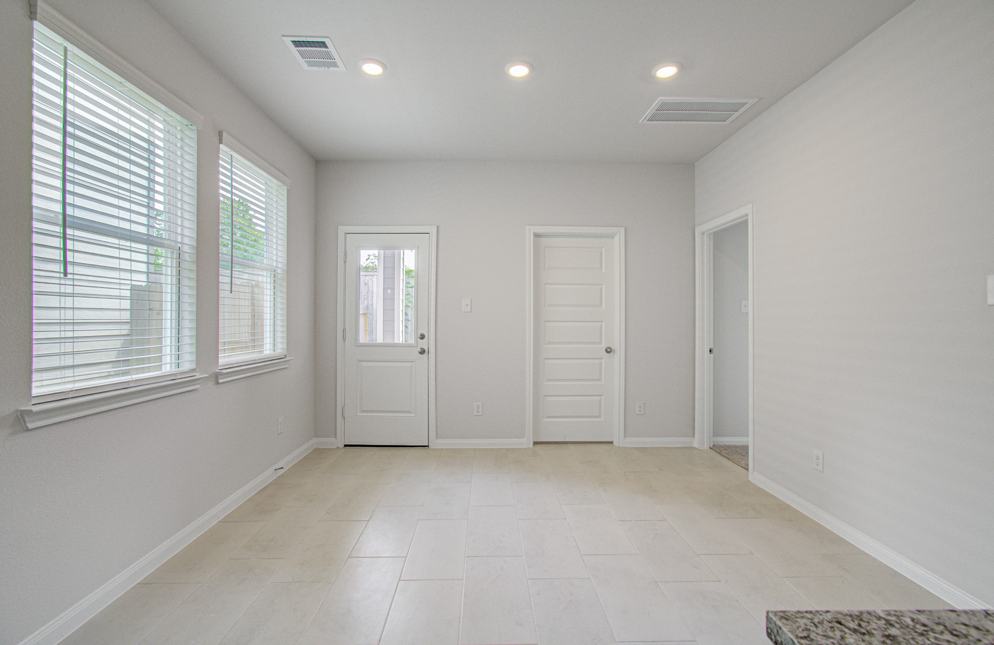 Bright, airy dining area  with large windows, tiled flooring, and modern recessed lighting, offering a clean and inviting space. Please Note this is a different home/floorplan in the community.