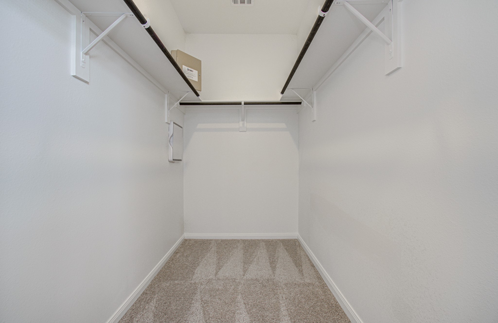 Spacious walk-in closet with dual hanging rods and plush carpeting, ideal for organizing your wardrobe. Please Note this is a different home/floorplan in the community.