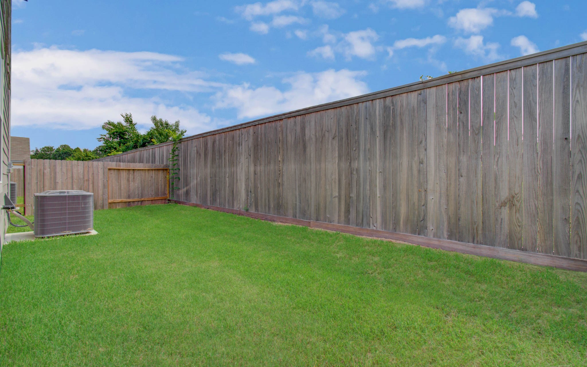 Spacious backyard with lush green grass and a privacy fence, perfect for outdoor activities and relaxation. Please Note this is a different home/floorplan in the community.