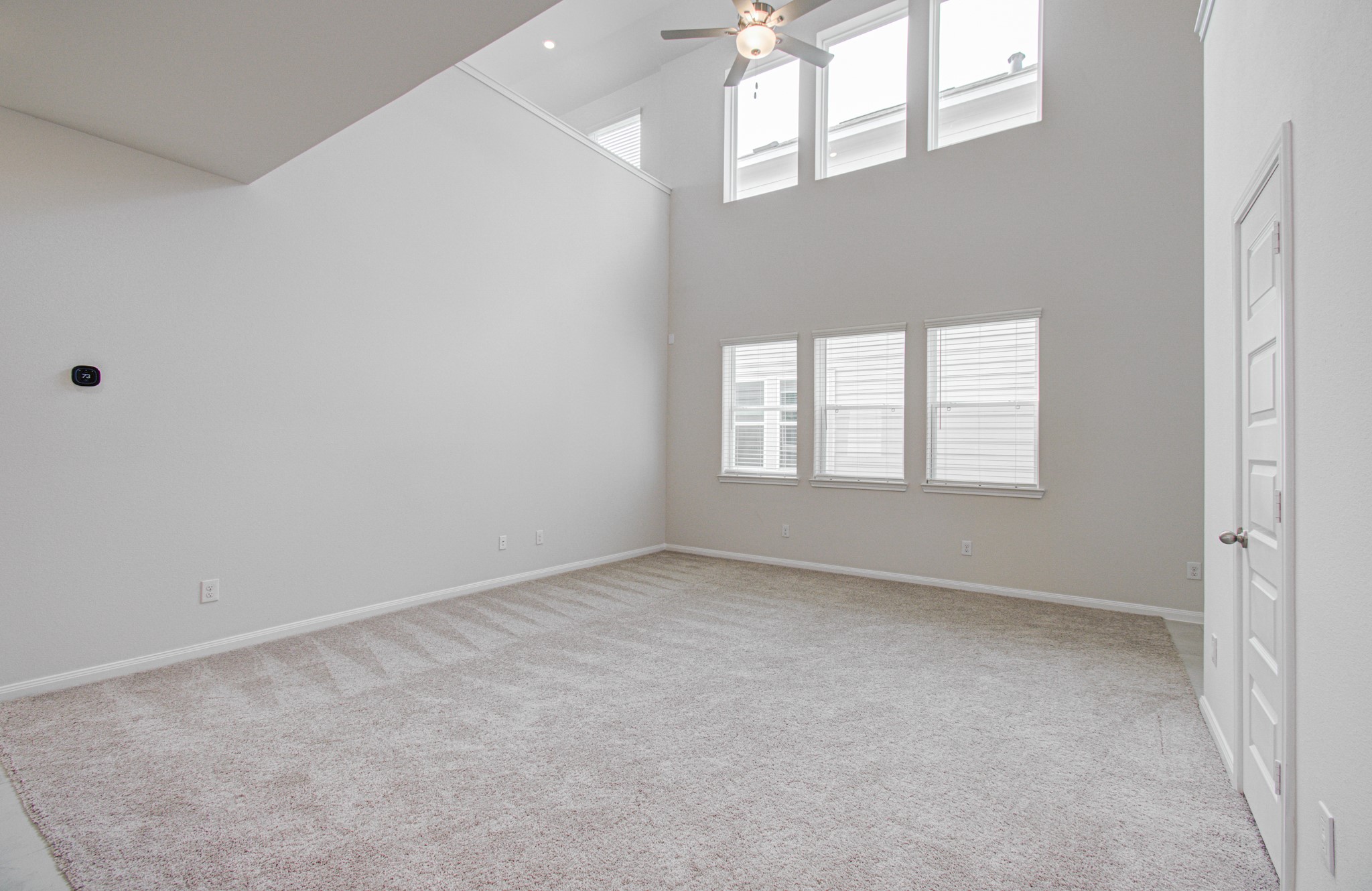 Expansive living area with soaring ceilings and abundant natural light from large windows, perfect for relaxation or entertaining. Please Note this is a different home/floorplan in the community.