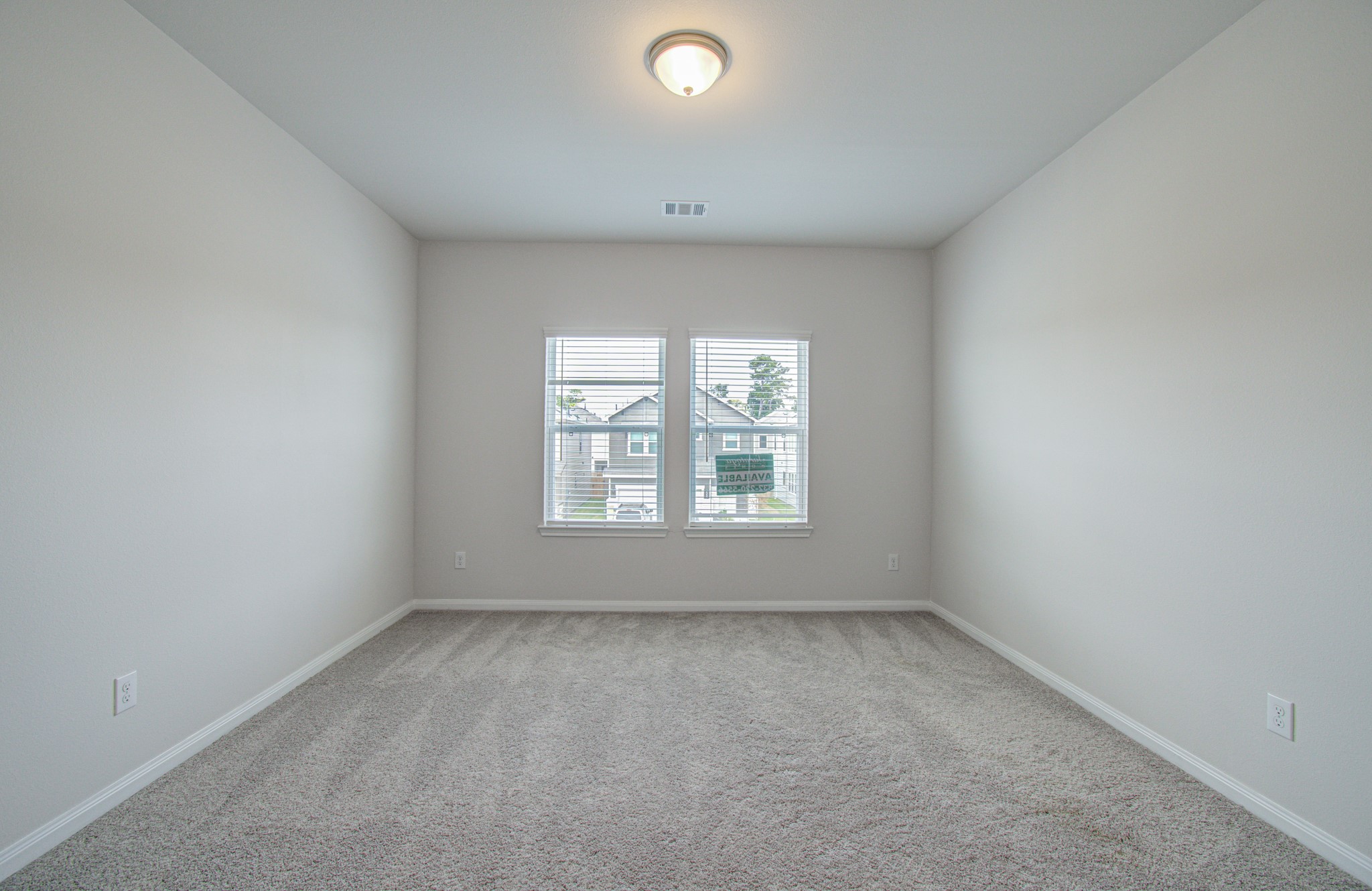 Bright and spacious bedroom with soft carpeting, neutral walls, and a large window that invites natural light. Please Note this is a different home/floorplan in the community.