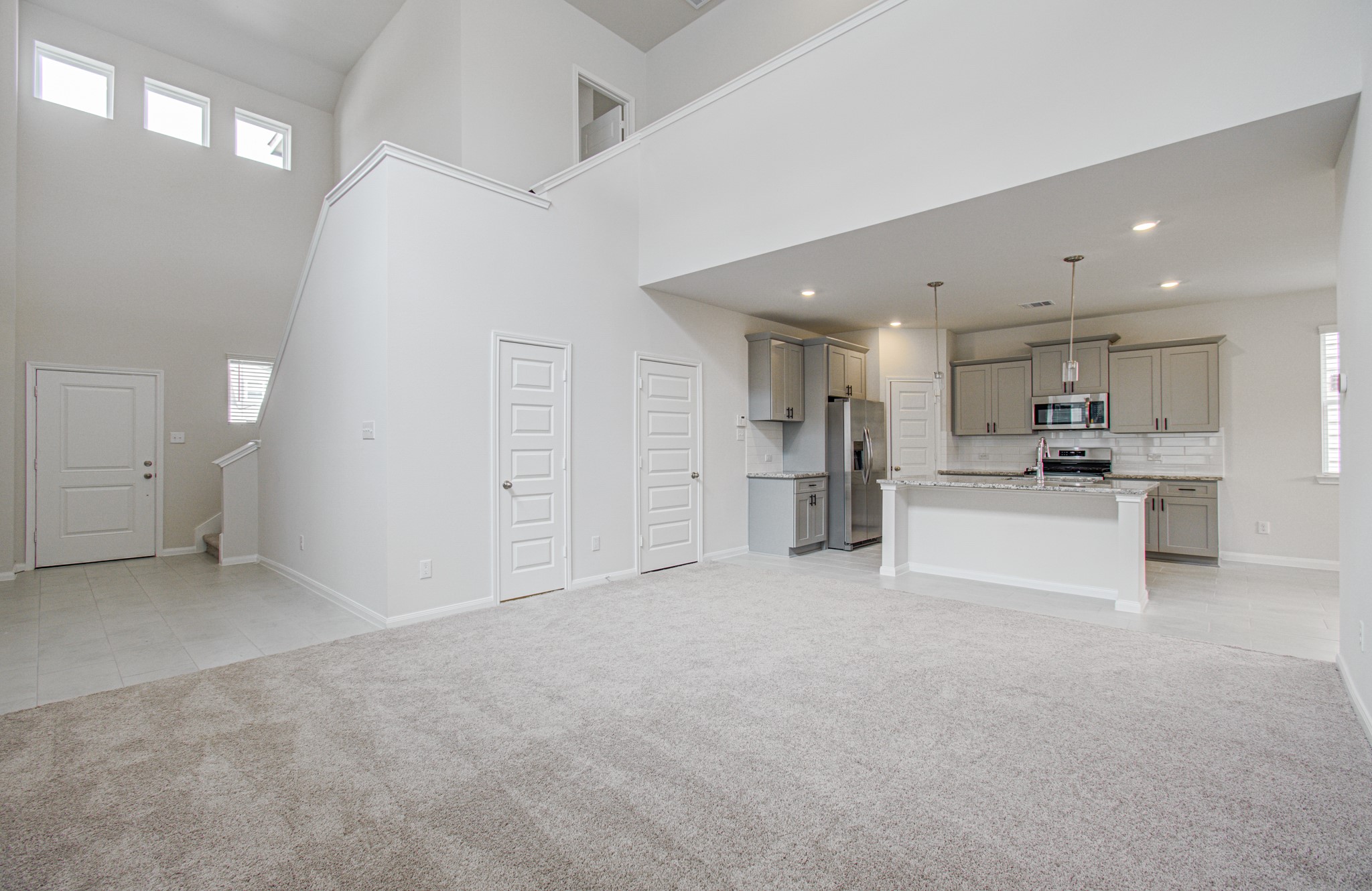 Spacious open-concept living  with high ceilings, modern kitchen featuring stainless steel appliances, and abundant natural light. Please Note this is a different home/floorplan in the community.