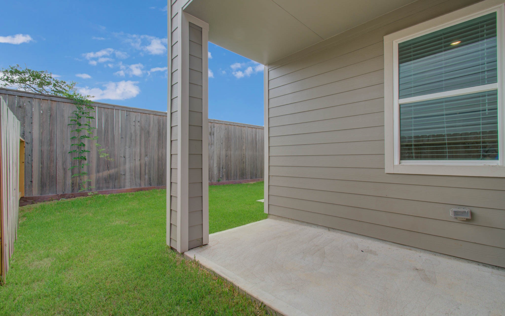 Cozy backyard with a well-maintained lawn, privacy fence, and a covered patio area perfect for relaxing outdoors. Please Note this is a different home/floorplan in the community.
