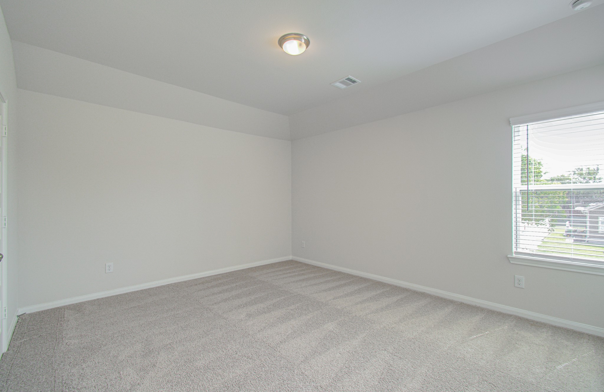 Spacious and bright third bedroom with soft carpet and a large window providing ample natural light. Please Note this is a different home/floorplan in the community.