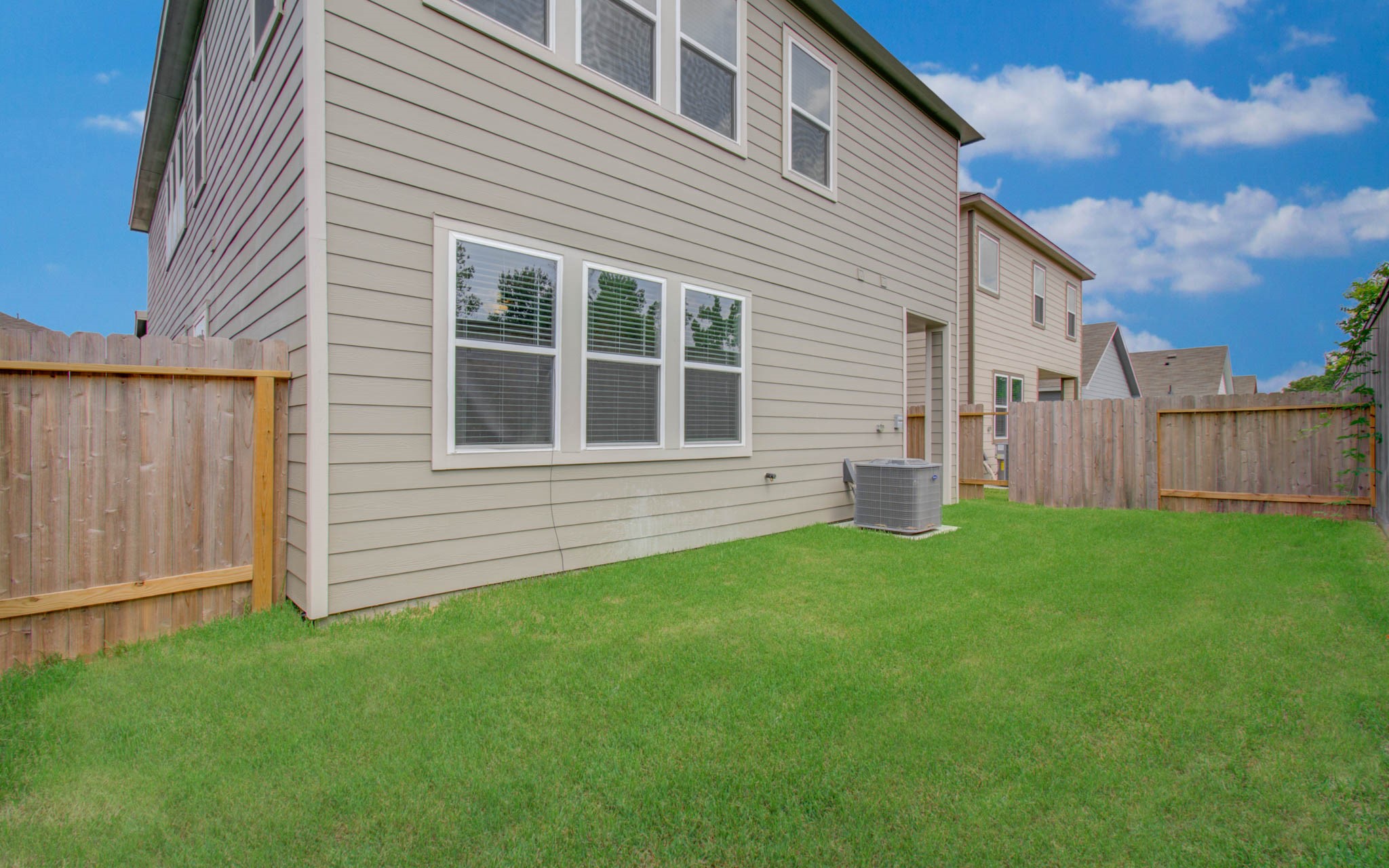Spacious backyard with well-maintained lawn, privacy fencing, and exterior access to the house, perfect for outdoor activities. Please Note this is a different home/floorplan in the community.