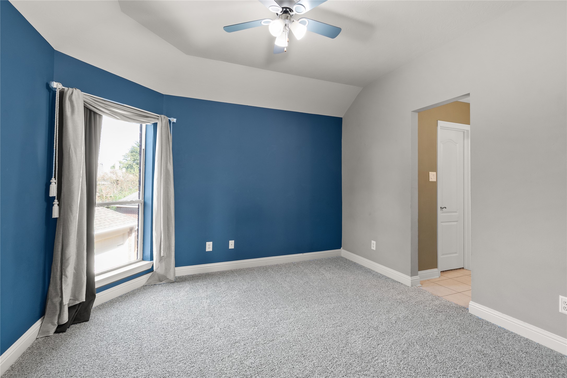 This inviting secondary bedroom features soft carpeting, a ceiling fan and natural light, providing a comfortable and versatile space for guests or everyday living.