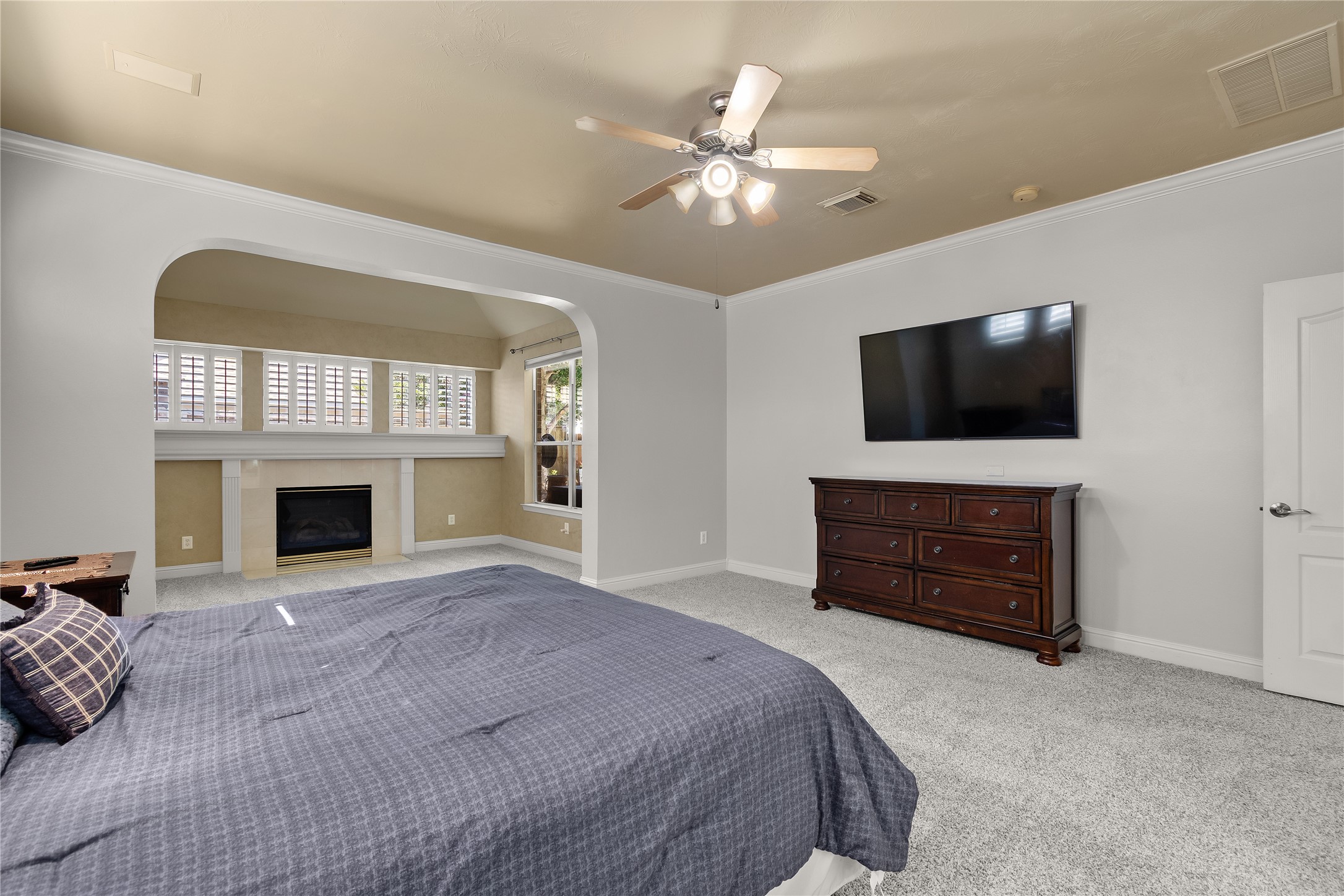 Escape to this inviting first-floor primary suite, featuring a ceiling fan, generous room dimensions and an adjoining sitting area with its own fireplace for added comfort.